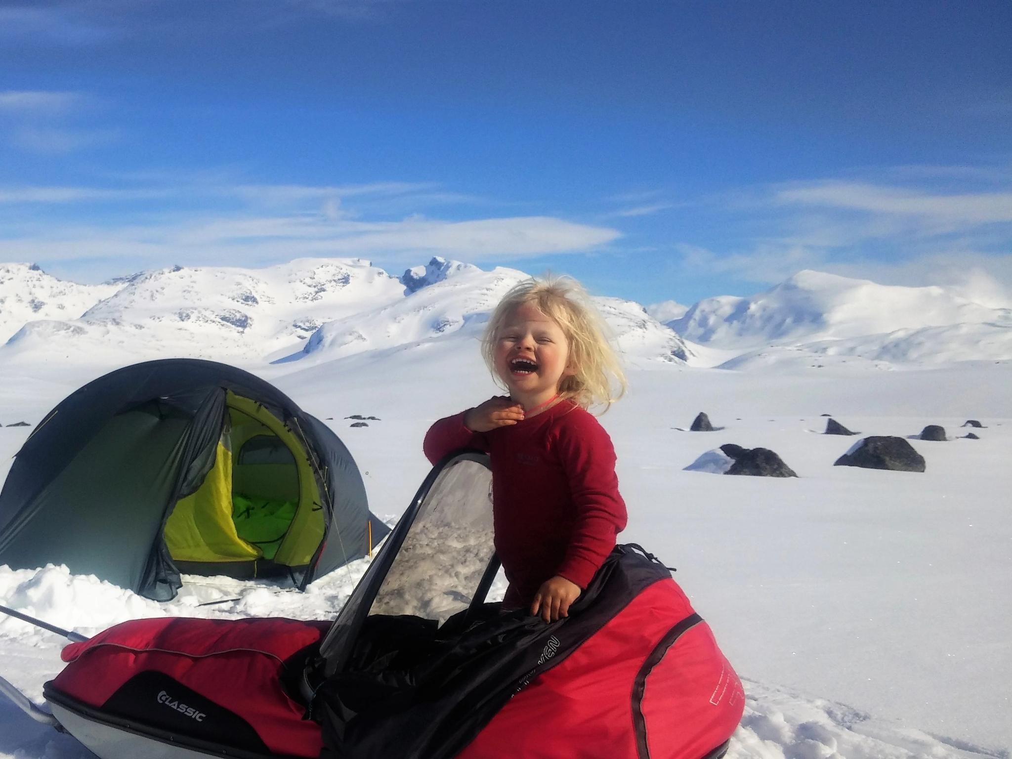 Die vierjährige Mina in einem Skipulk vor einem Zelt an einem sonnigen Wintertag in den Bergen des Jotunheimen Nationalparks