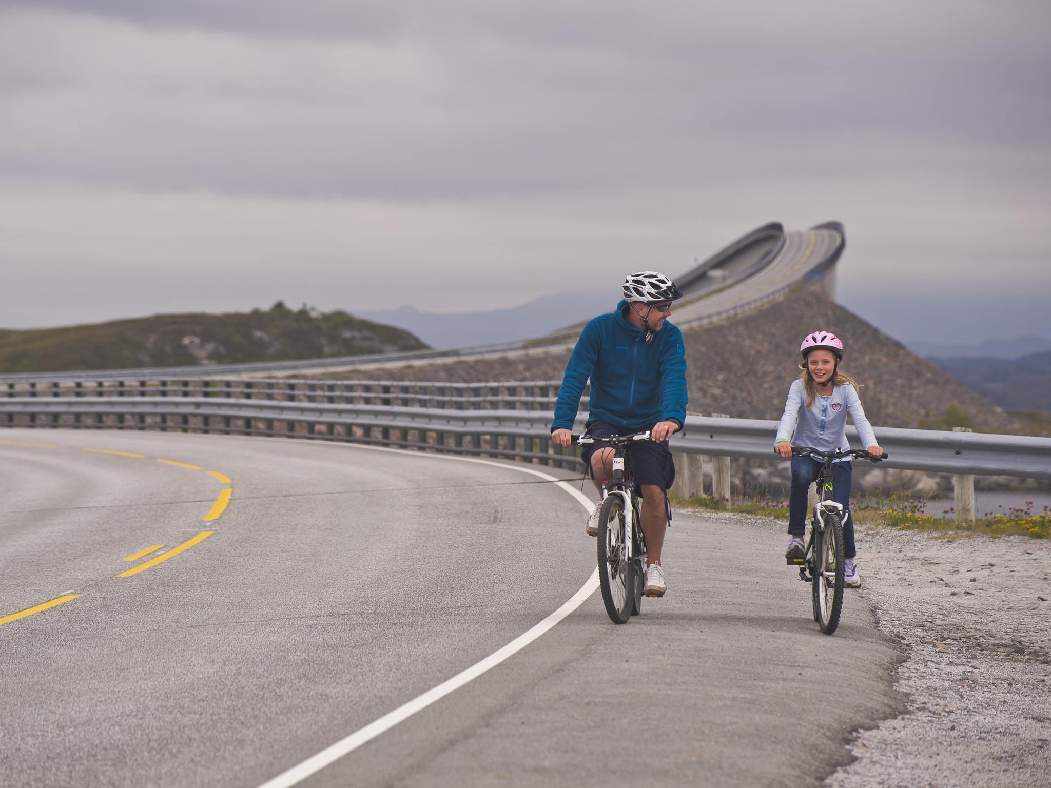 Far och dotter cyklar på Atlanterhavsvegen i Nordvest, som ligger i regionen Fjord Norge (Vestlandet)