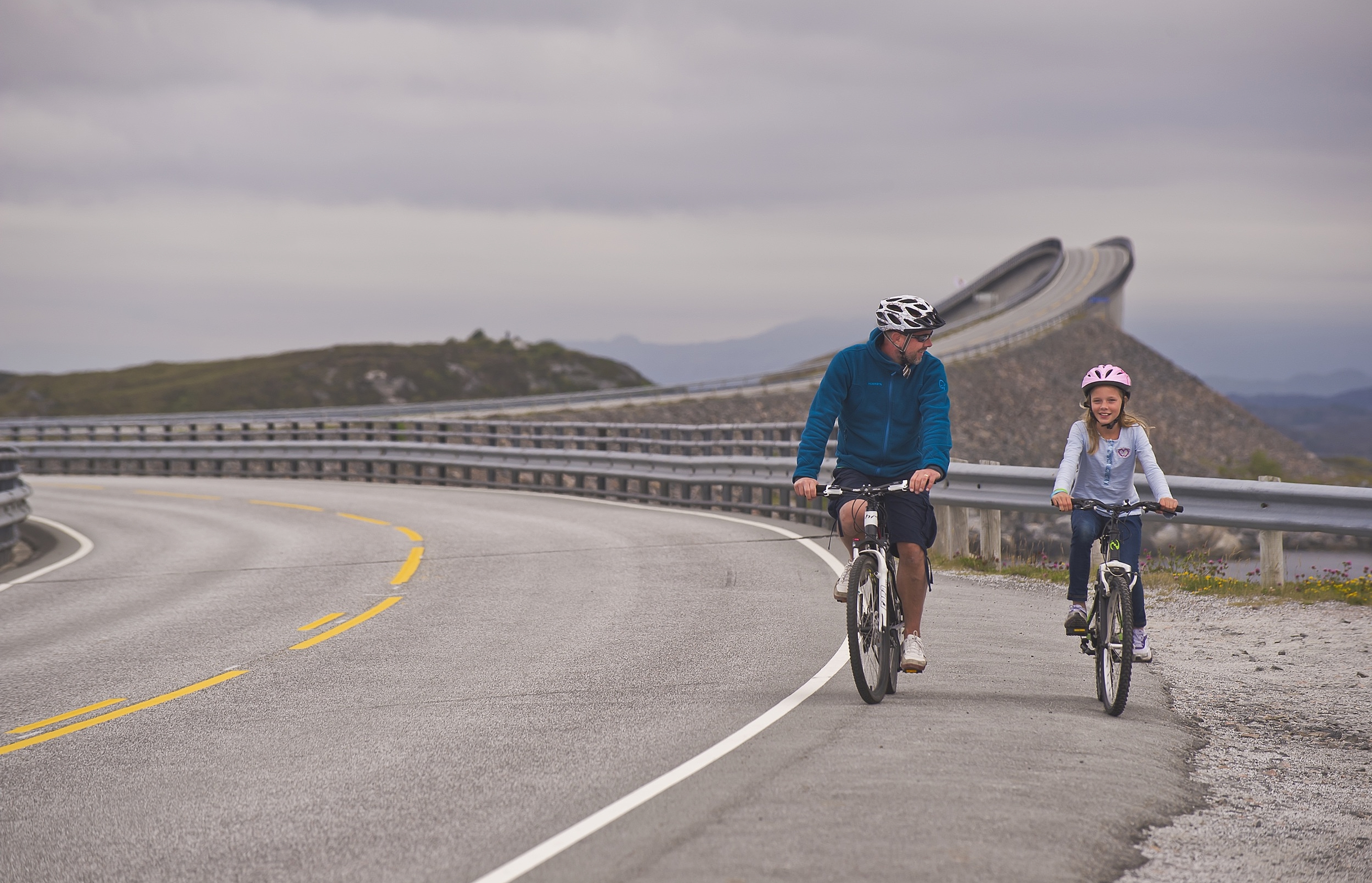 Father and daughter cycling on The Atlantic Road in the Northwest, Fjord Norway