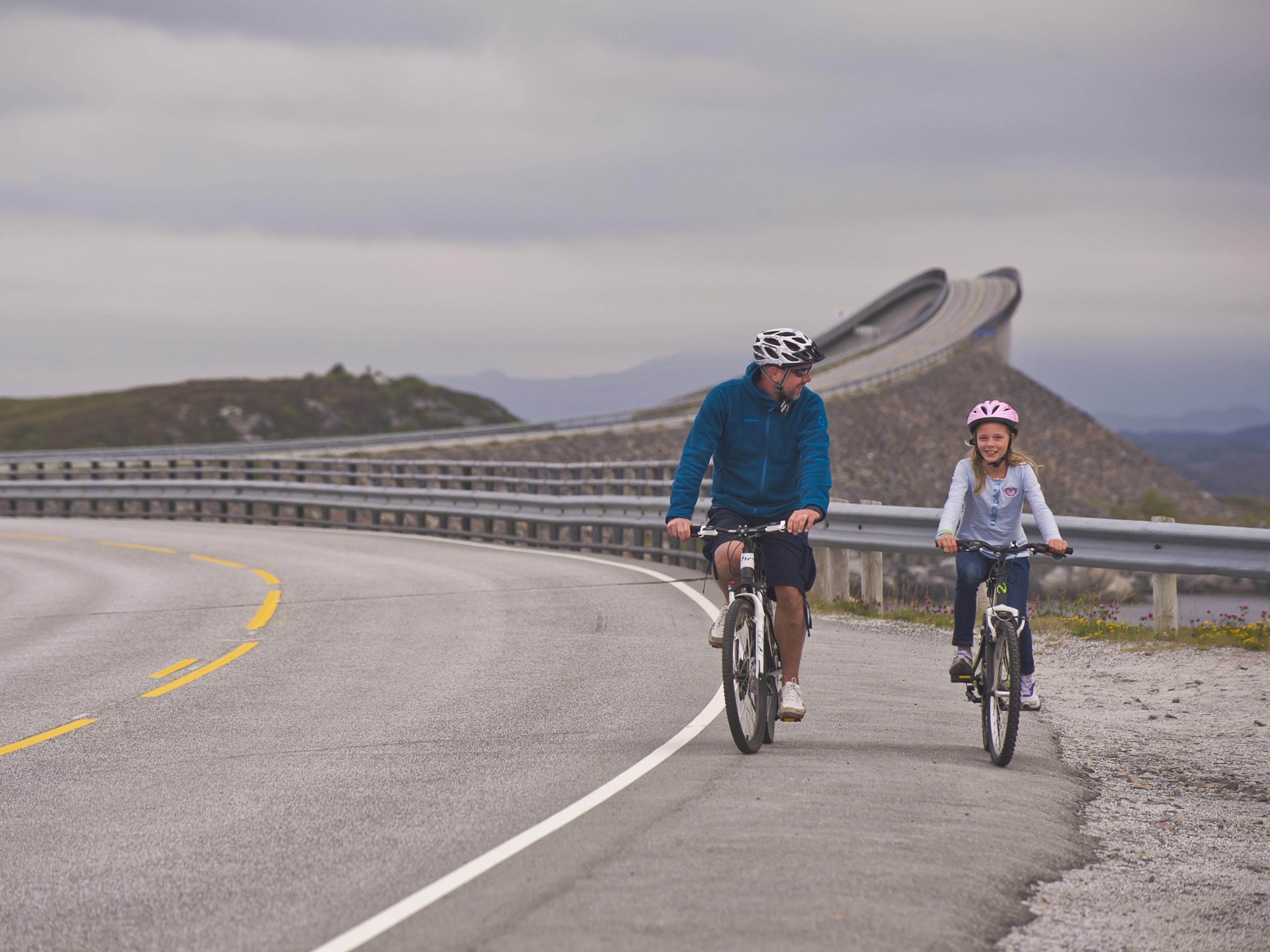 Father and daughter cycling on The Atlantic Road in the Northwest, Fjord Norway