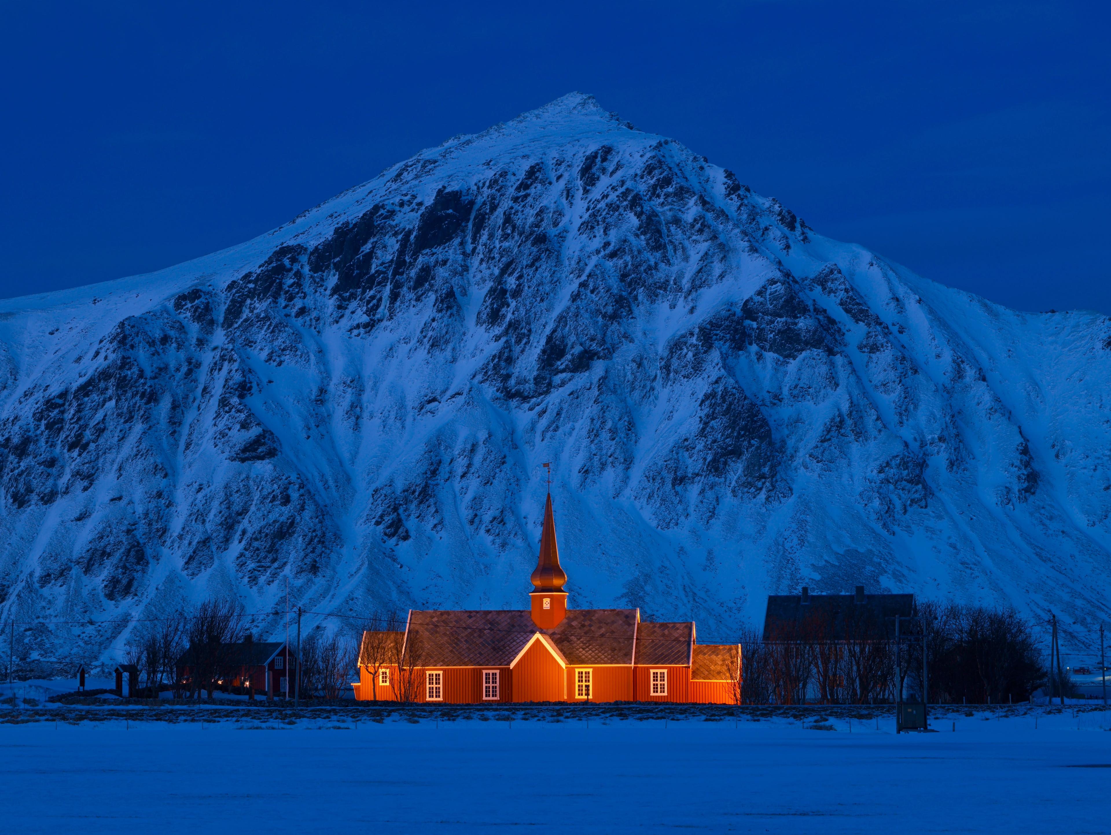 A lit up church in front of a steep mountain.