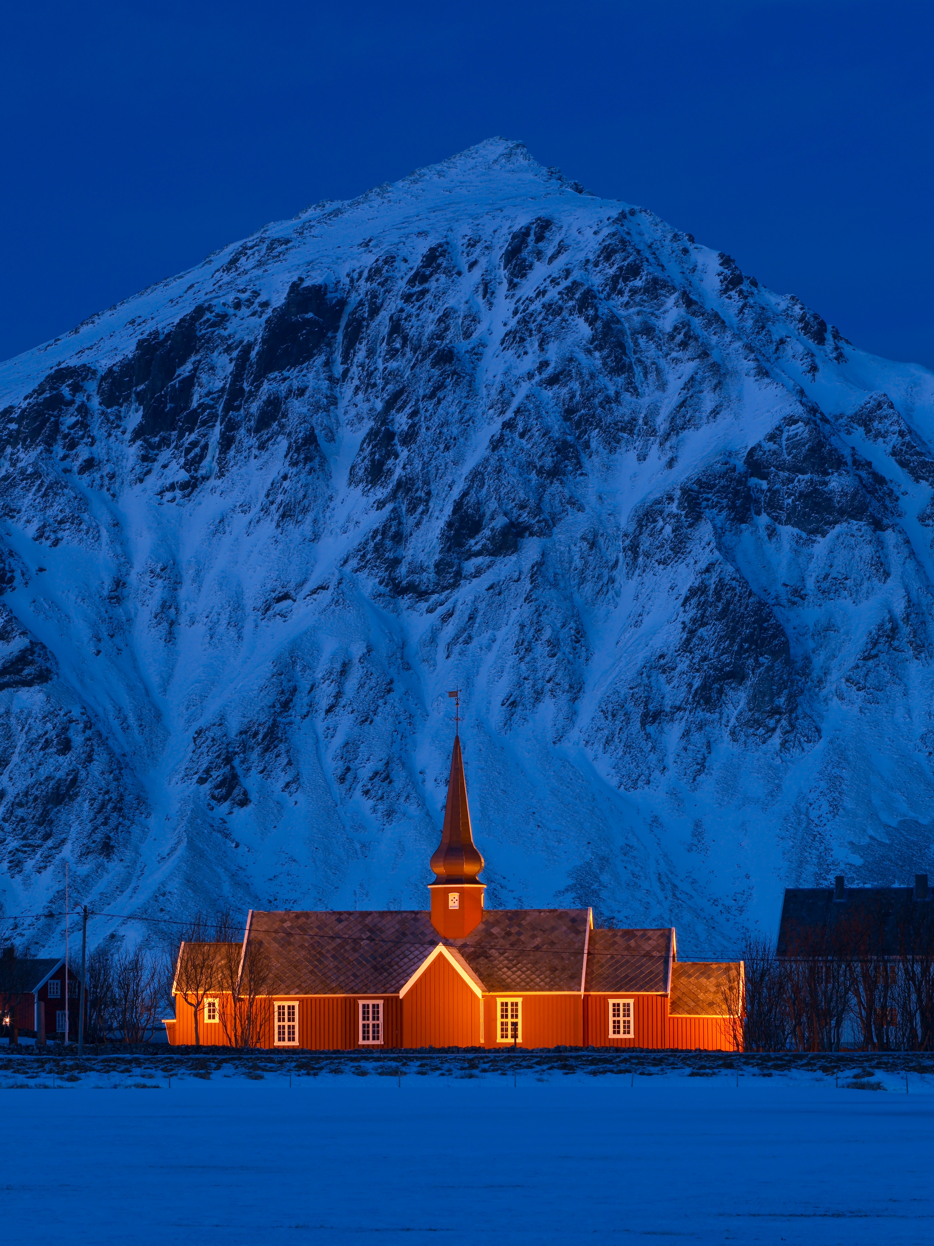 A lit up church in front of a steep mountain.