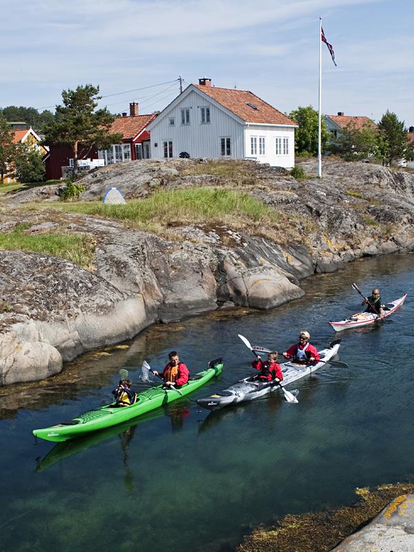 En familie padler i kajak i skærgården ud for Risør i det sydlige Norge