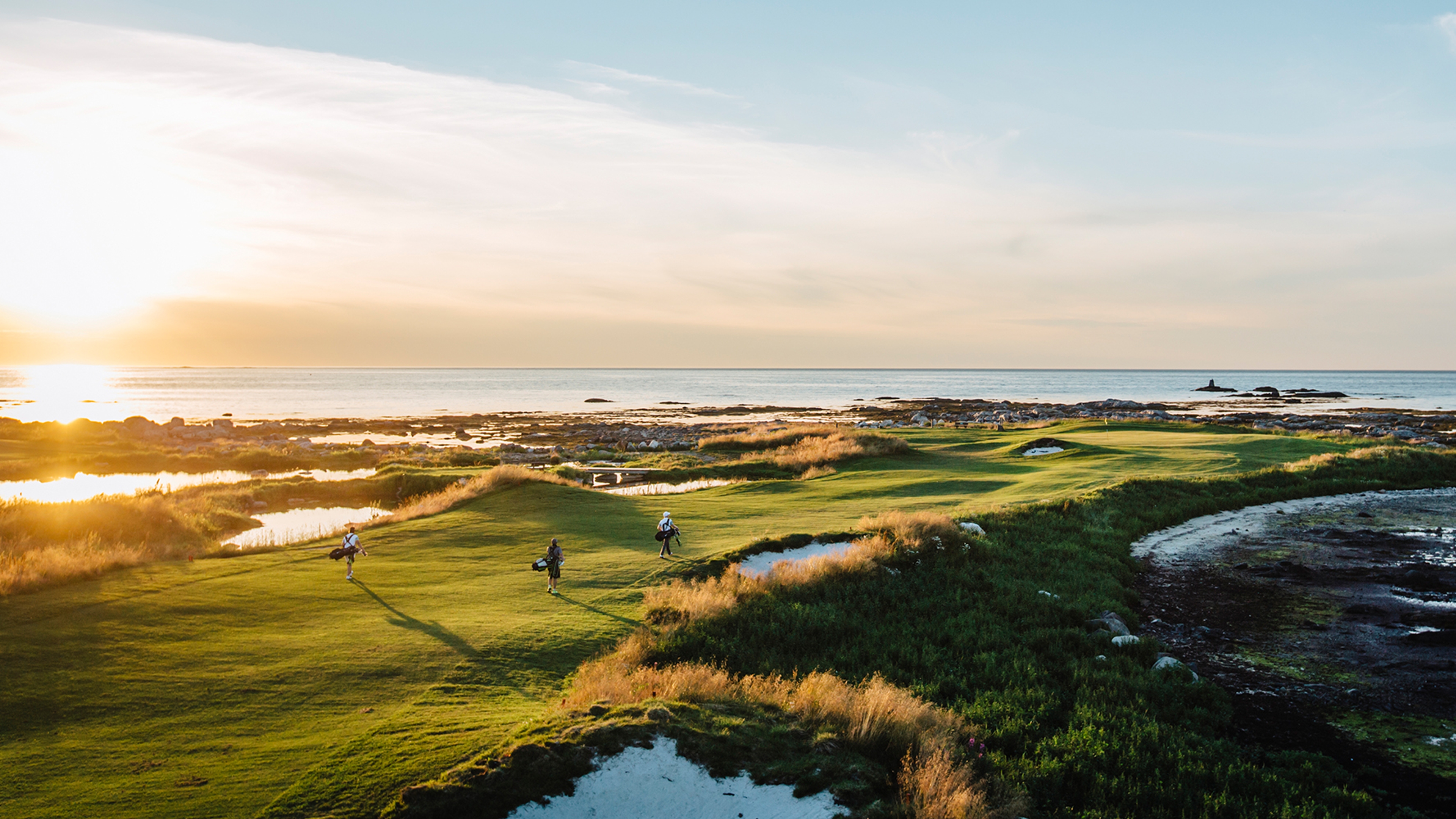 Three people playing golf under the midnight sun at Lofoten Links