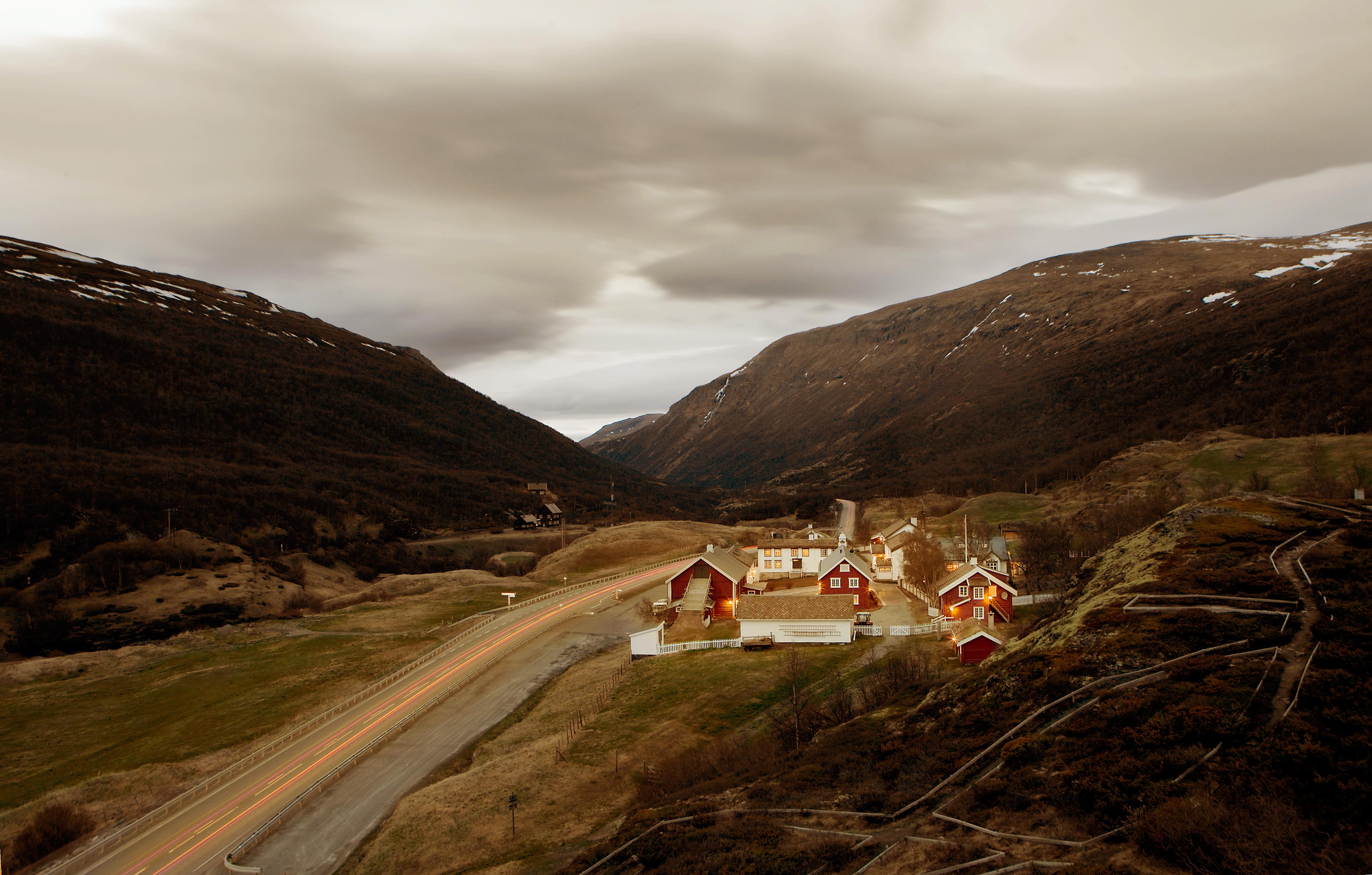Kongsvold Fjellstue in Dovrefjell. It is surrounded by mountains and with a road going past on the left.