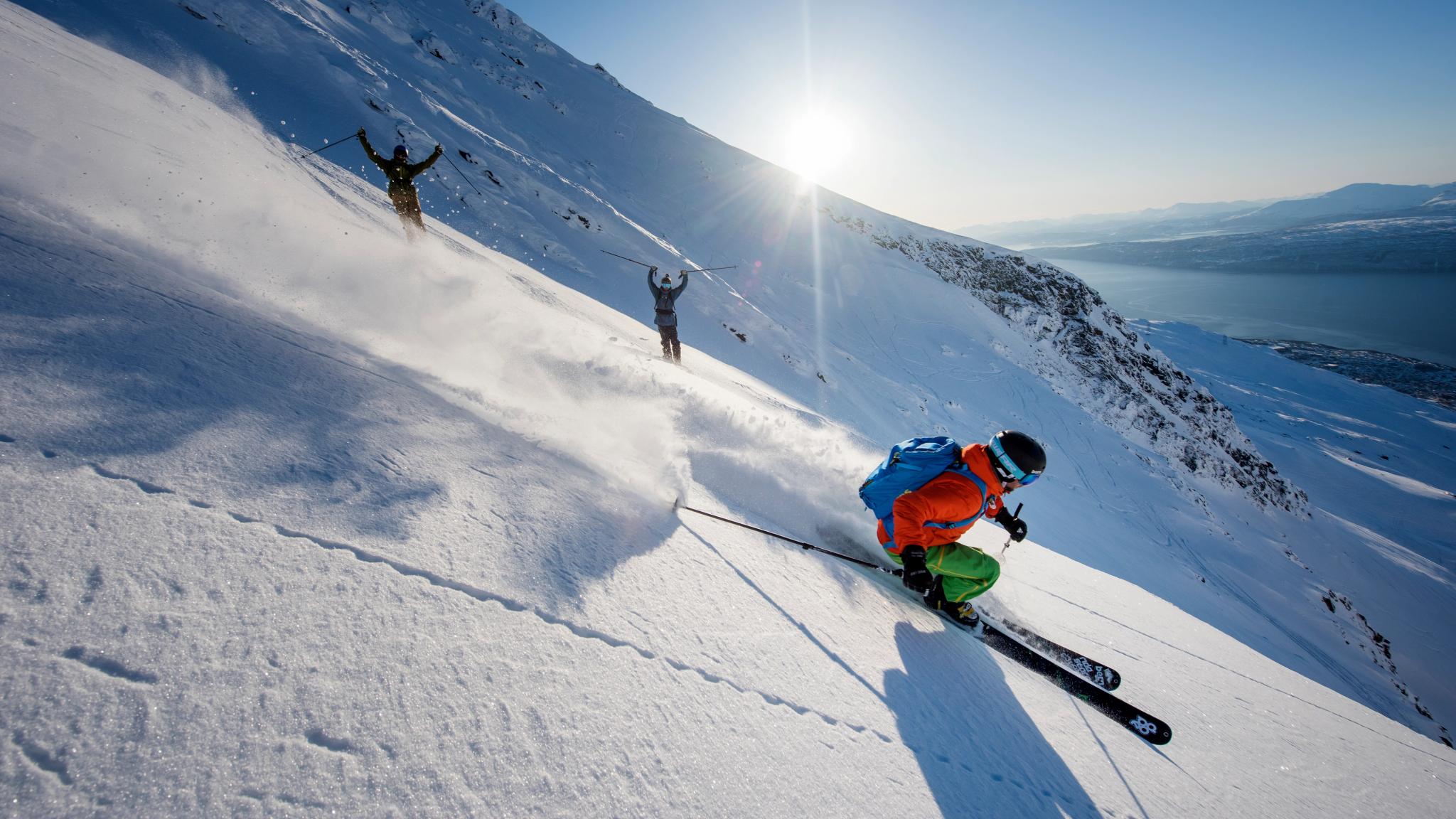 Someone skiing down a mountain with two people cheering in the background