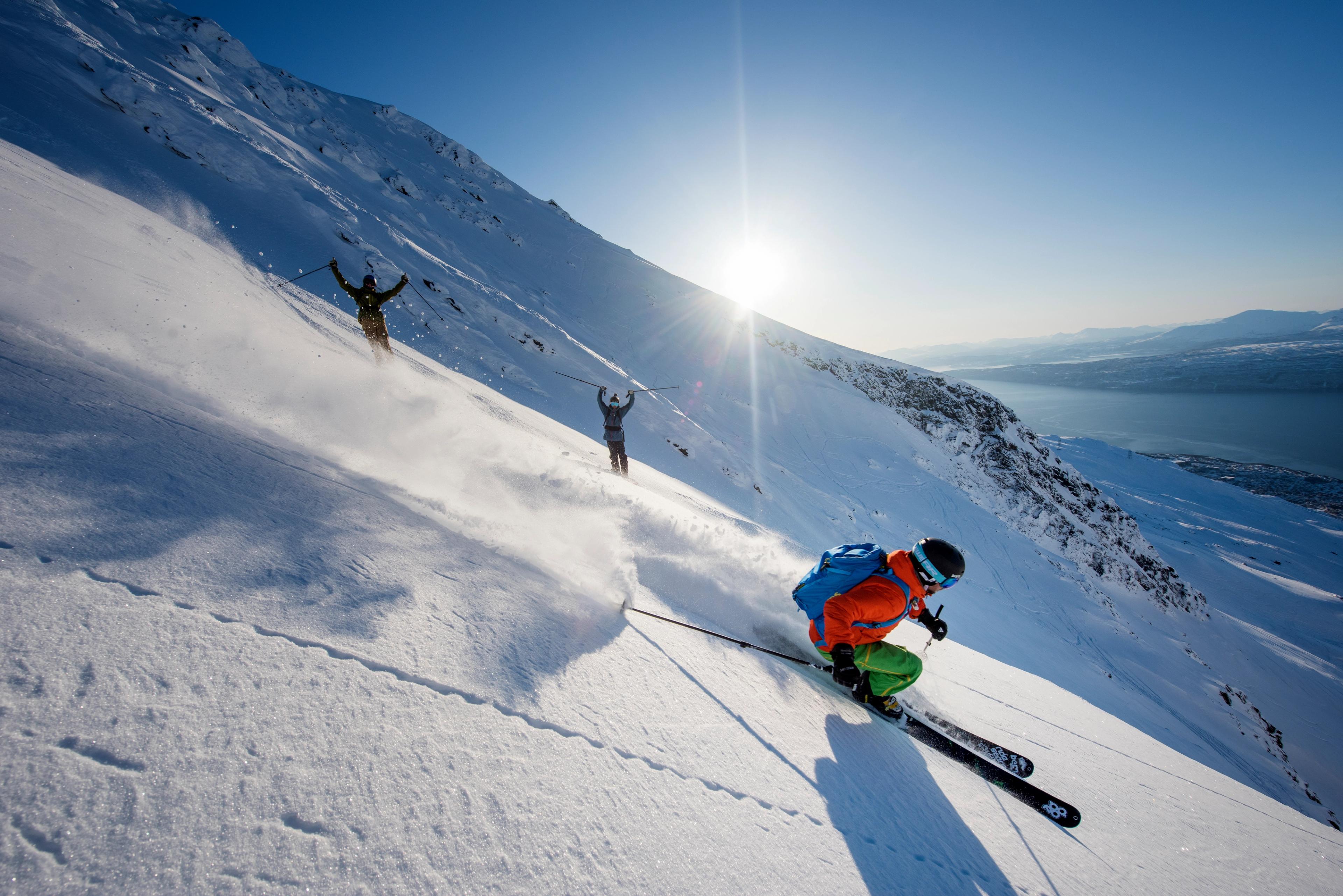 Someone skiing down a mountain with two people cheering in the background