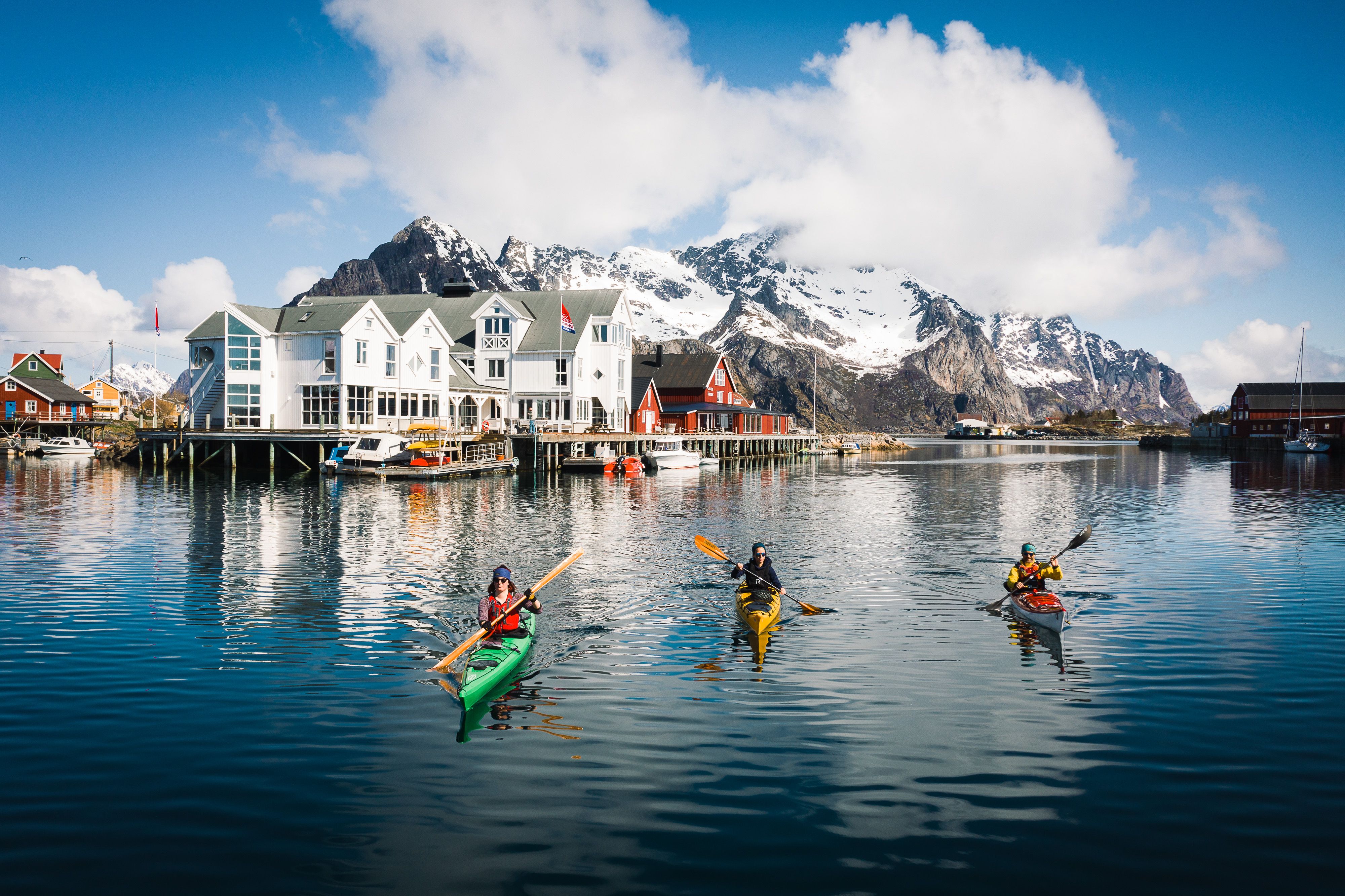 People winter kayaking by the Henningsvær Bryggehotell in Lofoten, Northern Norway.