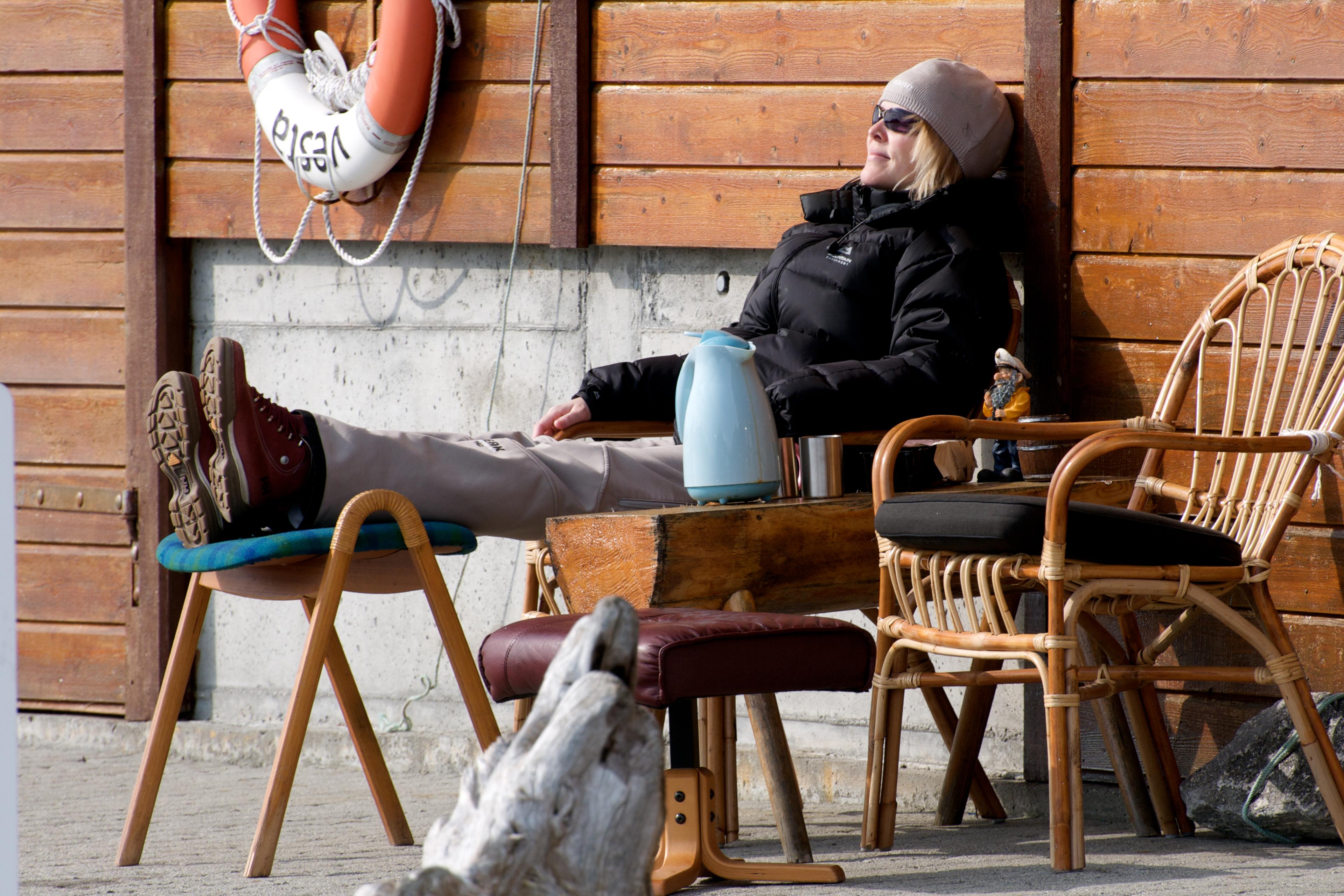 A woman is enjoying the sun by the fjord in the Sunnmøre region of Fjord Norway.