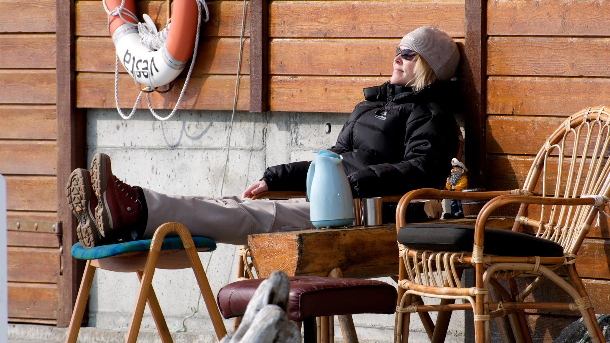 A woman is enjoying the sun by the fjord in the Sunnmøre region of Fjord Norway.