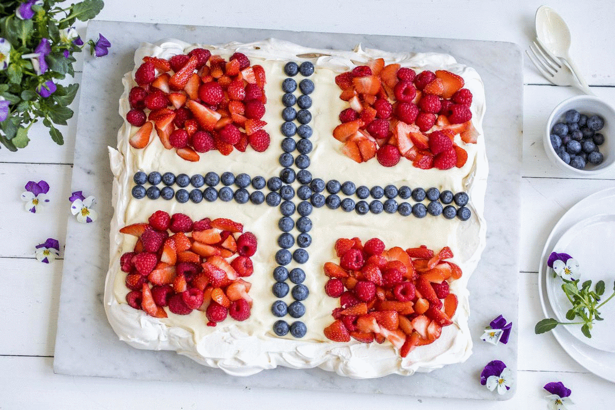 A pavlova decorated with berries in the pattern of the Norwegian flag