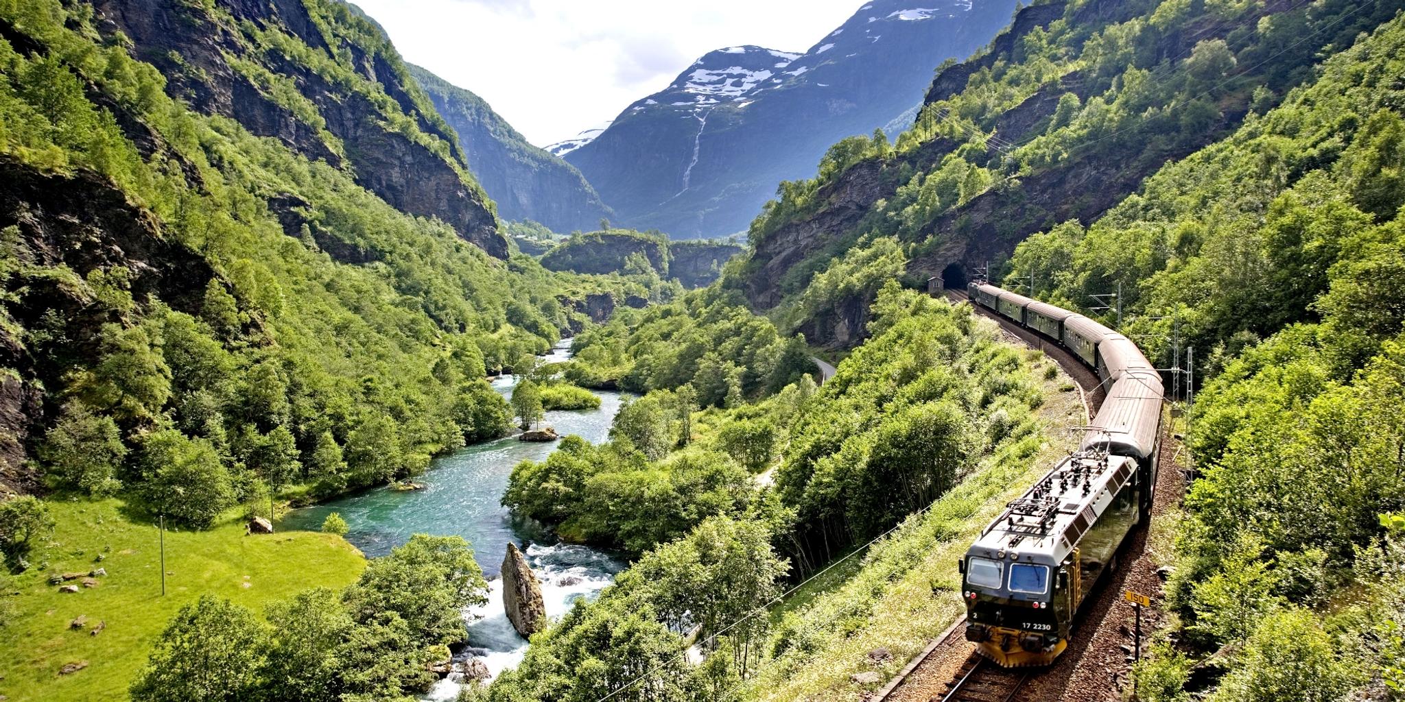 The Flåm Railway going through the landscape of green hills and spectacular mountains in Fjord Norway