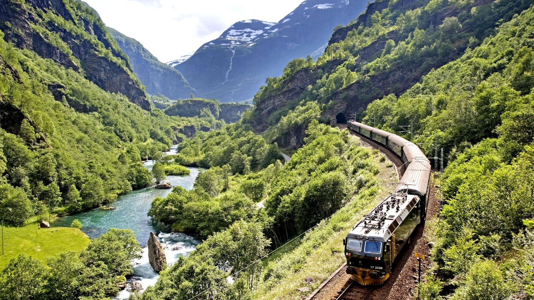 The Flåm Railway going through the landscape of green hills and spectacular mountains in Fjord Norway