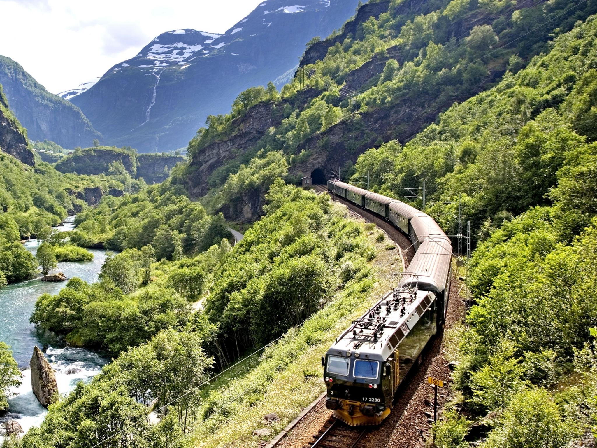 The Flåm Railway going through the landscape of green hills and spectacular mountains in Fjord Norway