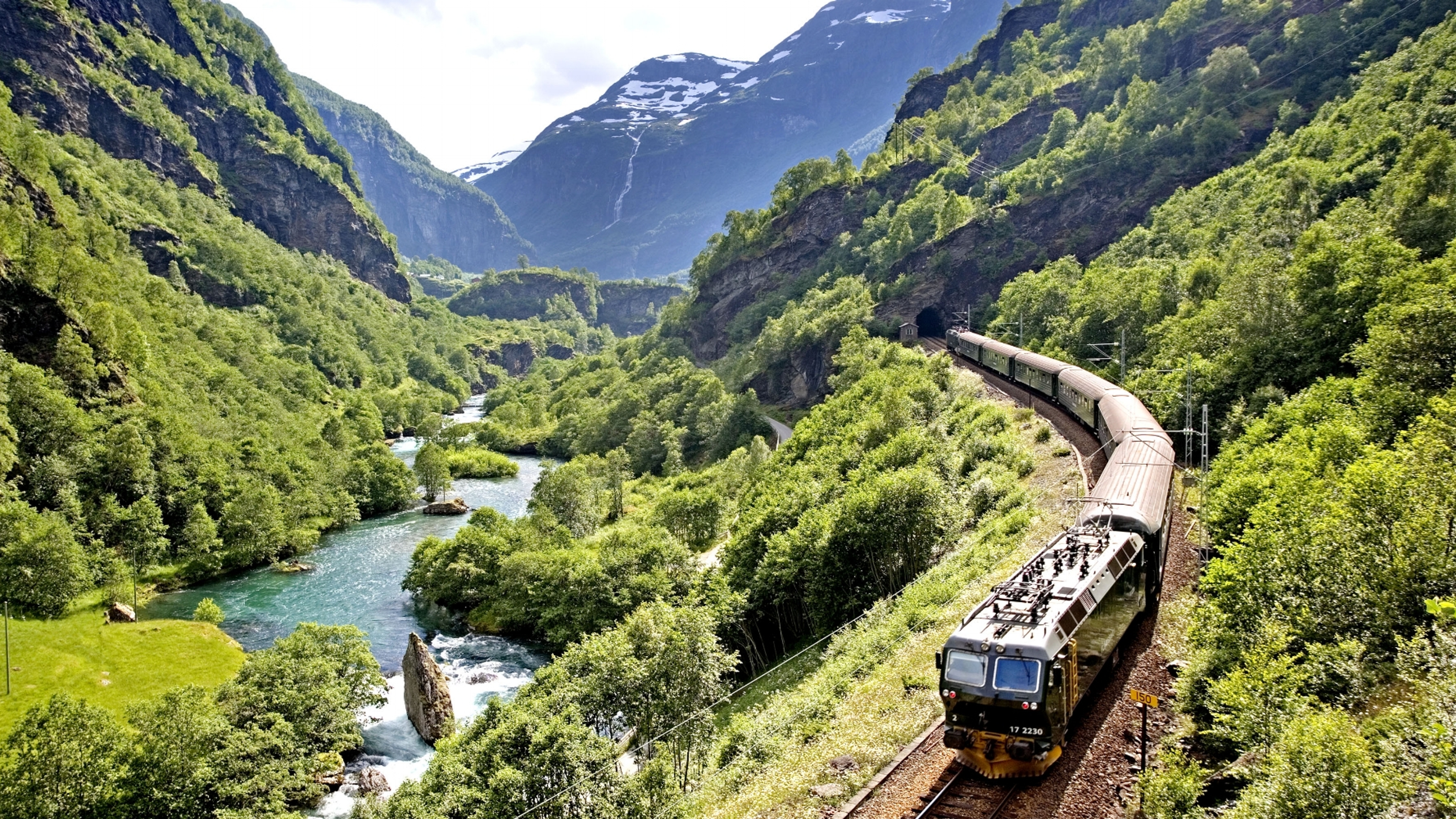 The Flåm Railway going through the landscape of green hills and spectacular mountains in Fjord Norway