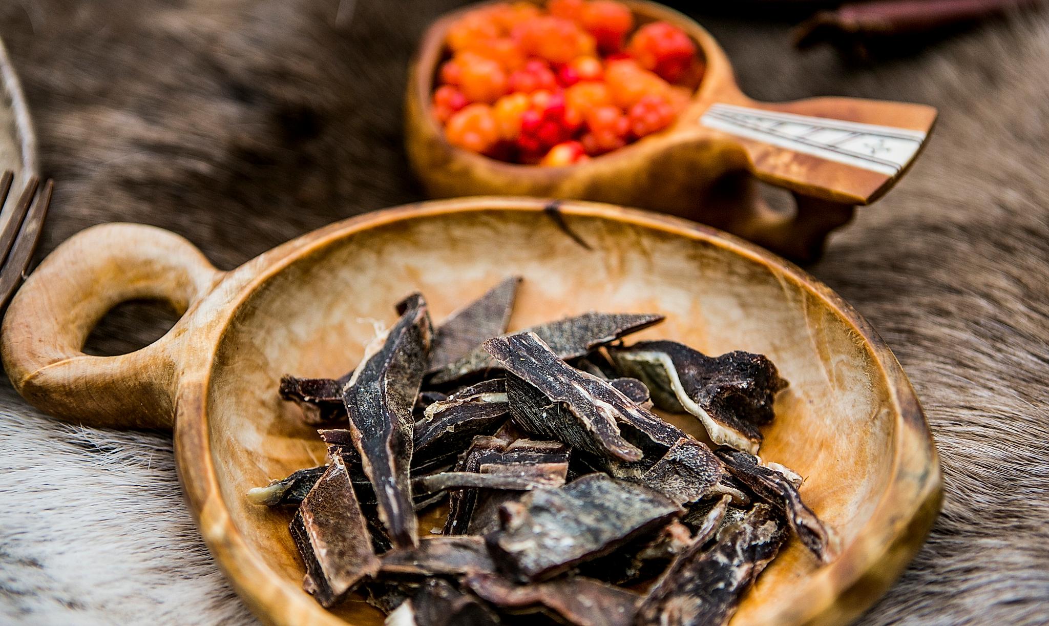Curend reindeer meat on a plate and cloudberries in a bowl in Finnmark, Northern Norway