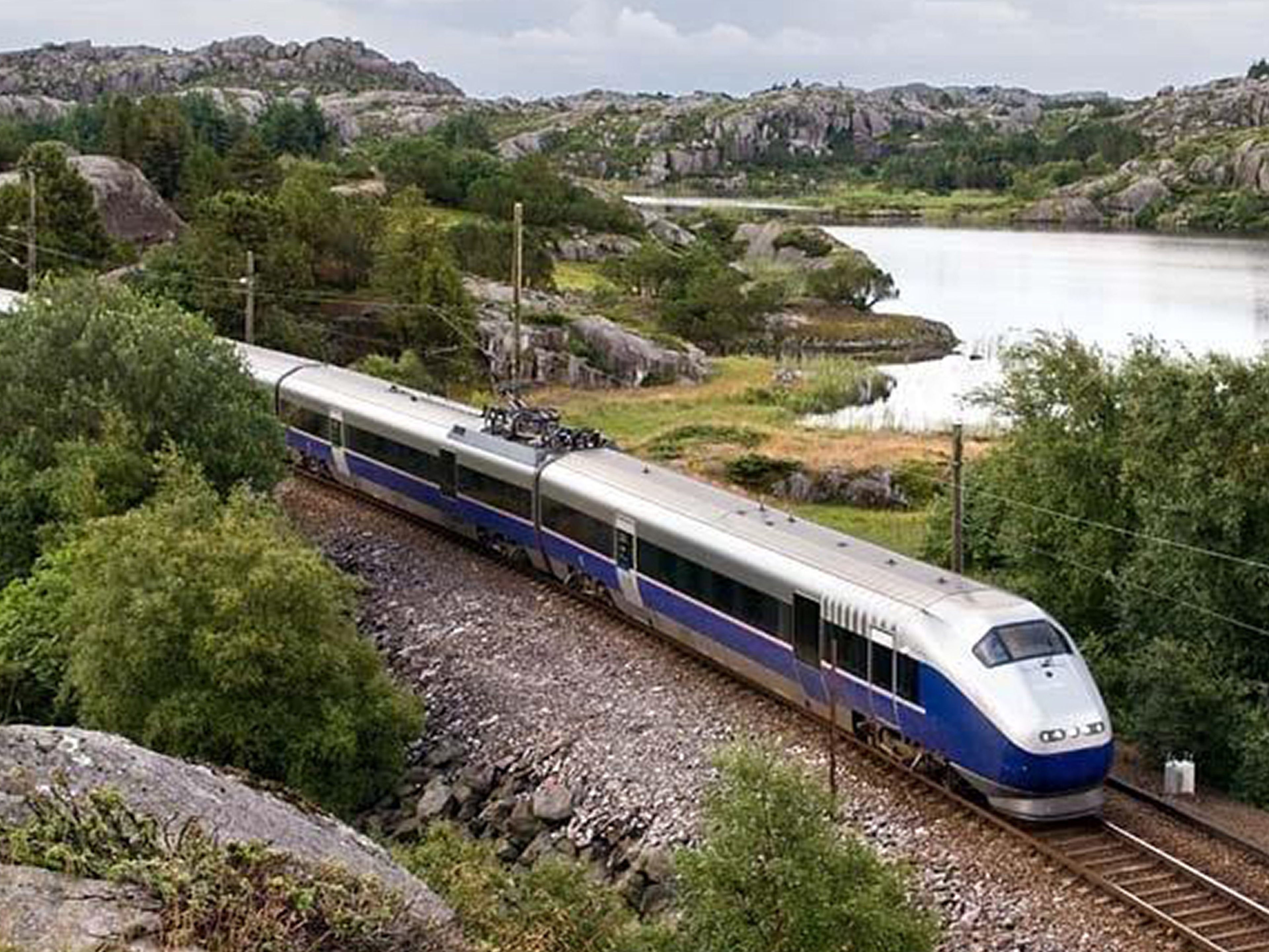 A train passes a lake along the Jærbanen in Fjord Norway
