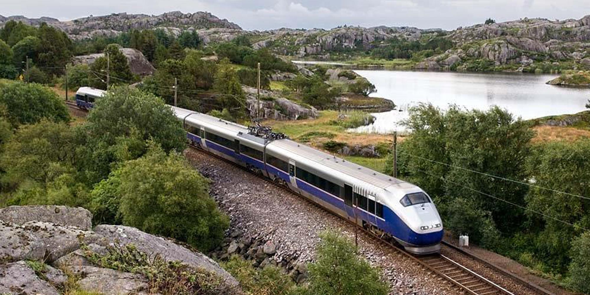 A train passes a lake along the Jærbanen in Fjord Norway
