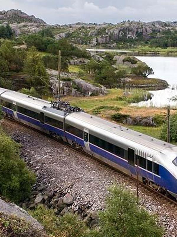 A train passes a lake along the Jærbanen in Fjord Norway