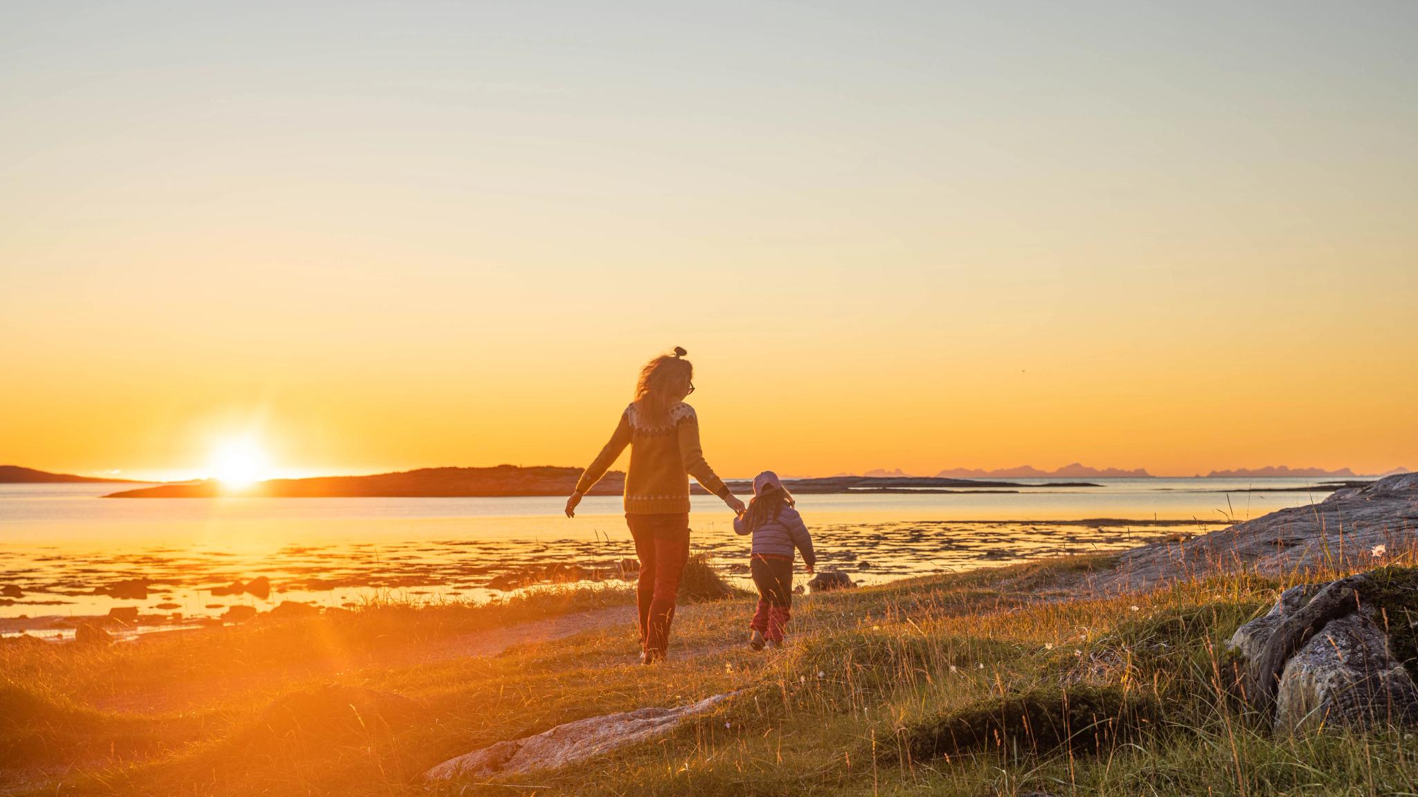 A woman and a child enjoying a sunset on the beach.