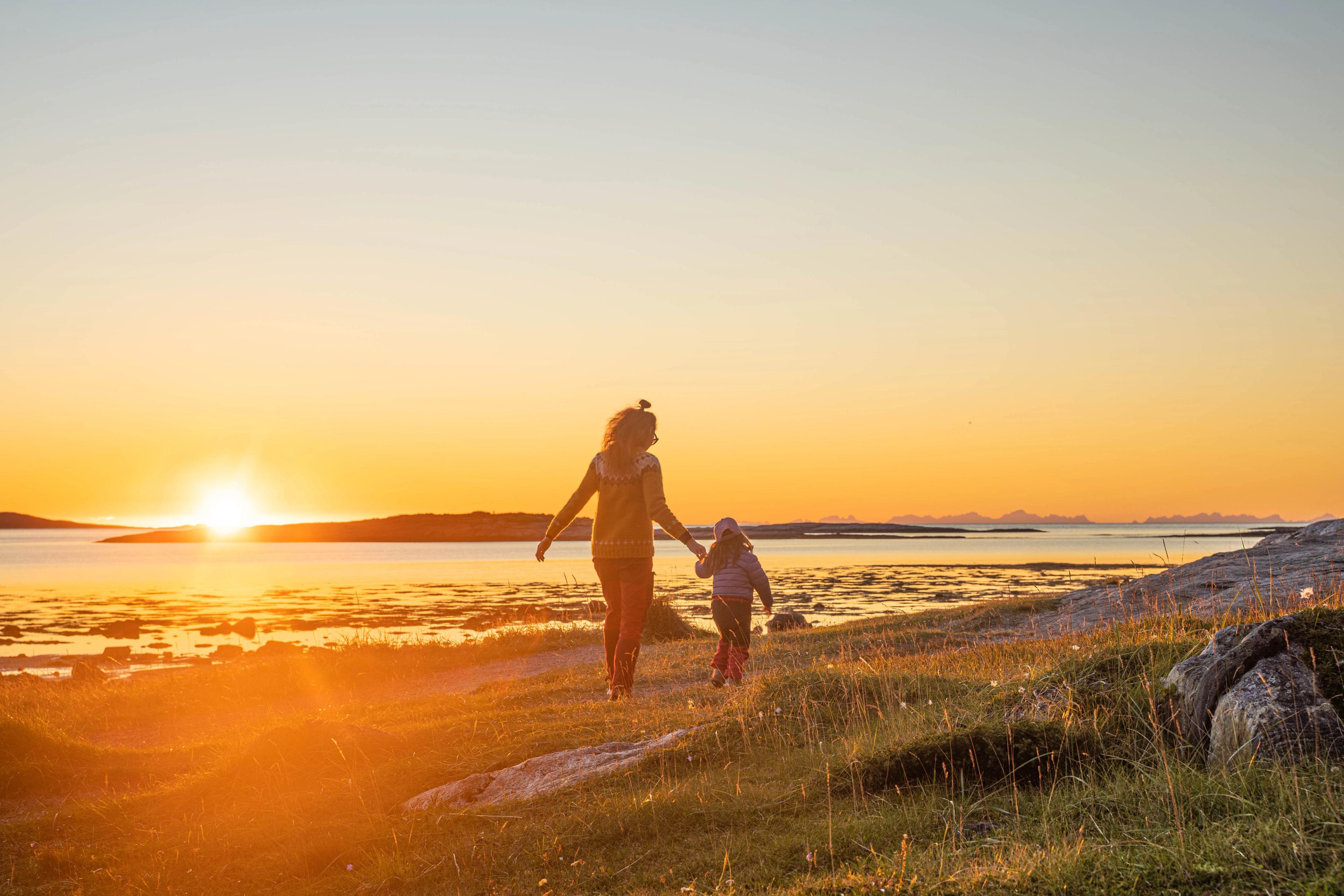 A woman and a child enjoying a sunset on the beach.