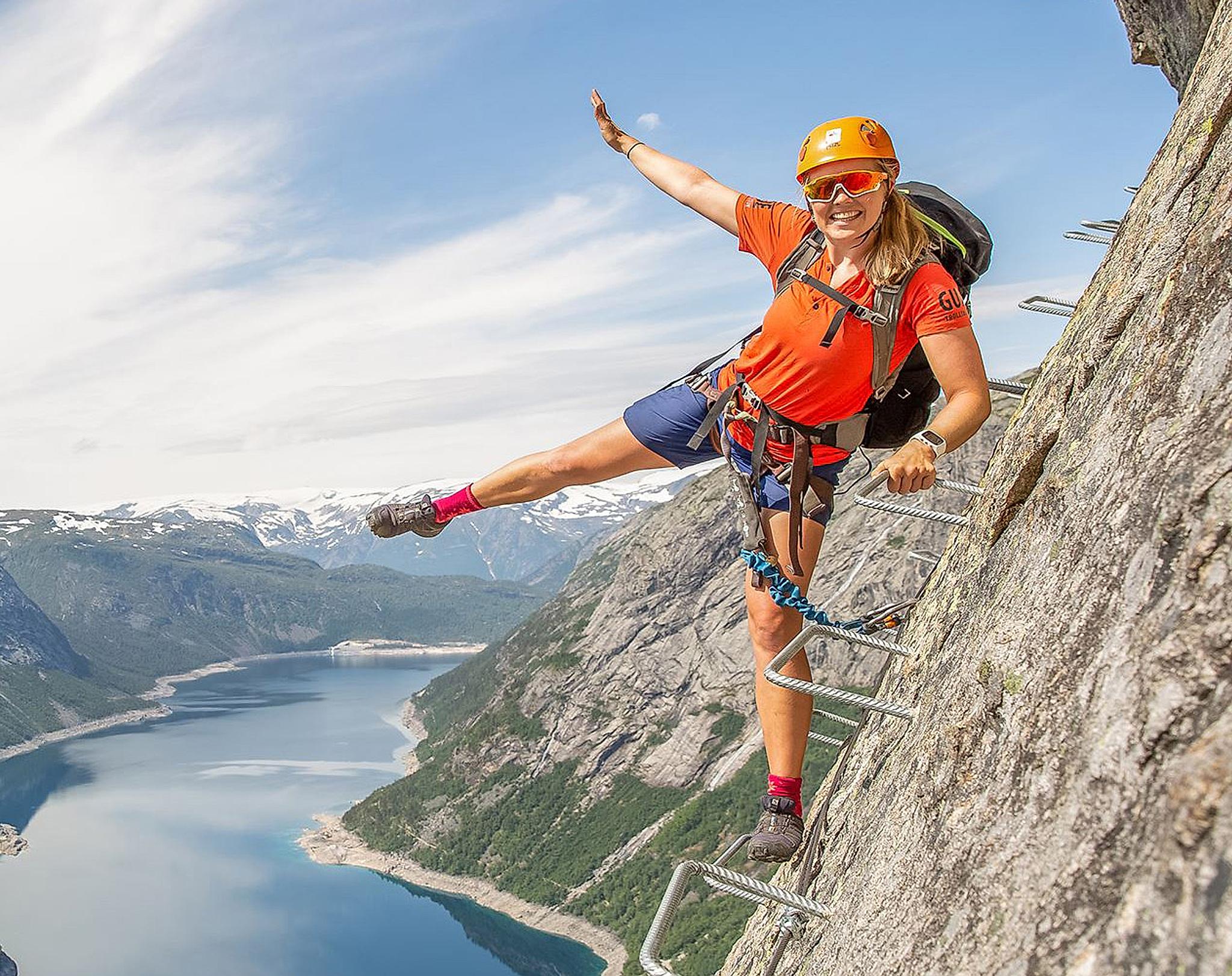 En pige klatrer på via ferrataen til Trolltunga på en solskinsdag