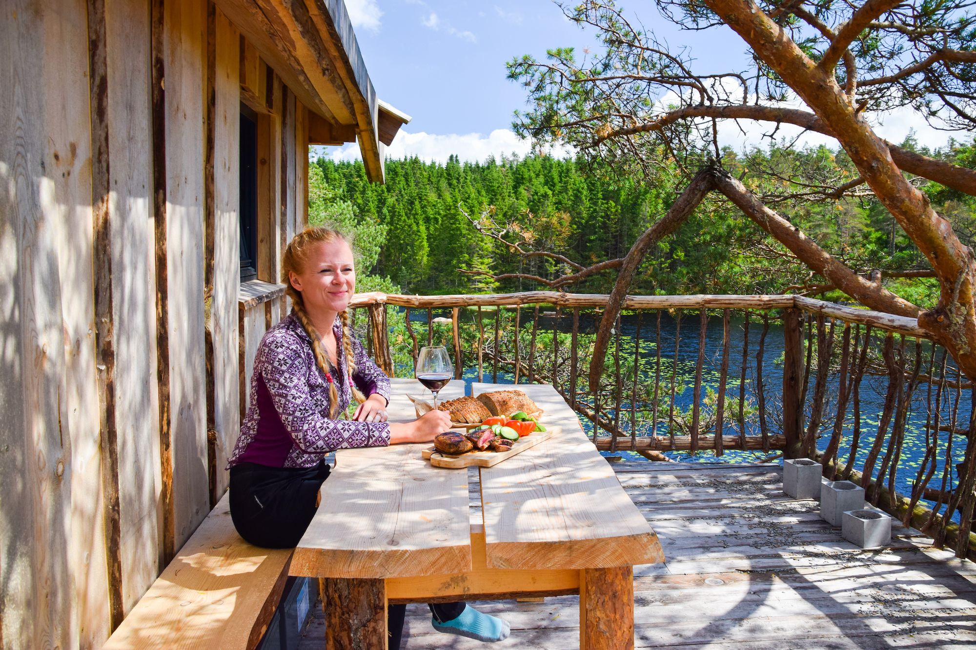 Girl eating on the terrace at a tree top cabin, Southern Norway