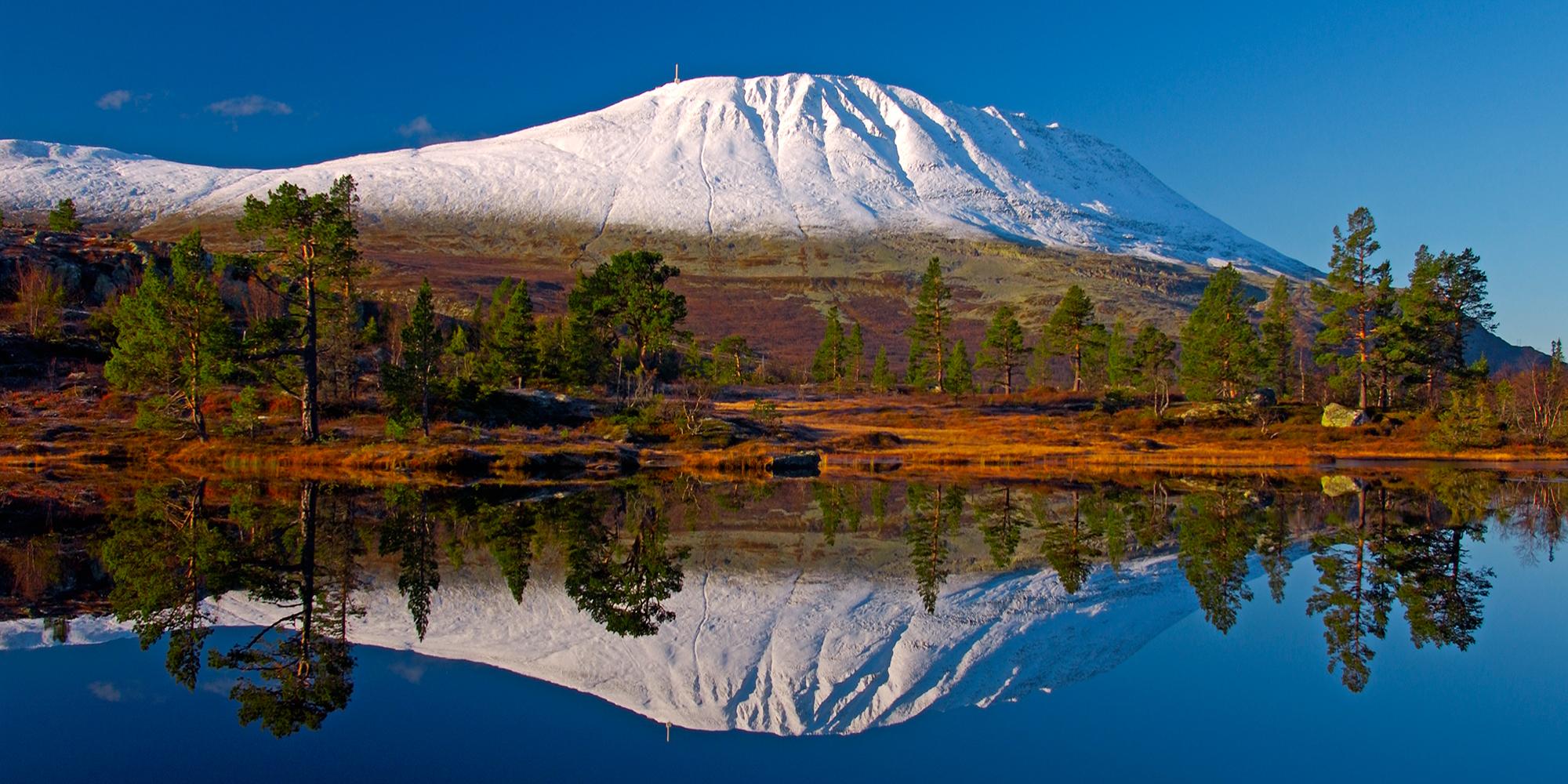 Een besneeuwde berg Gaustatoppen die in het meer gereflecteerd wordt. Telemark, Noorwegen