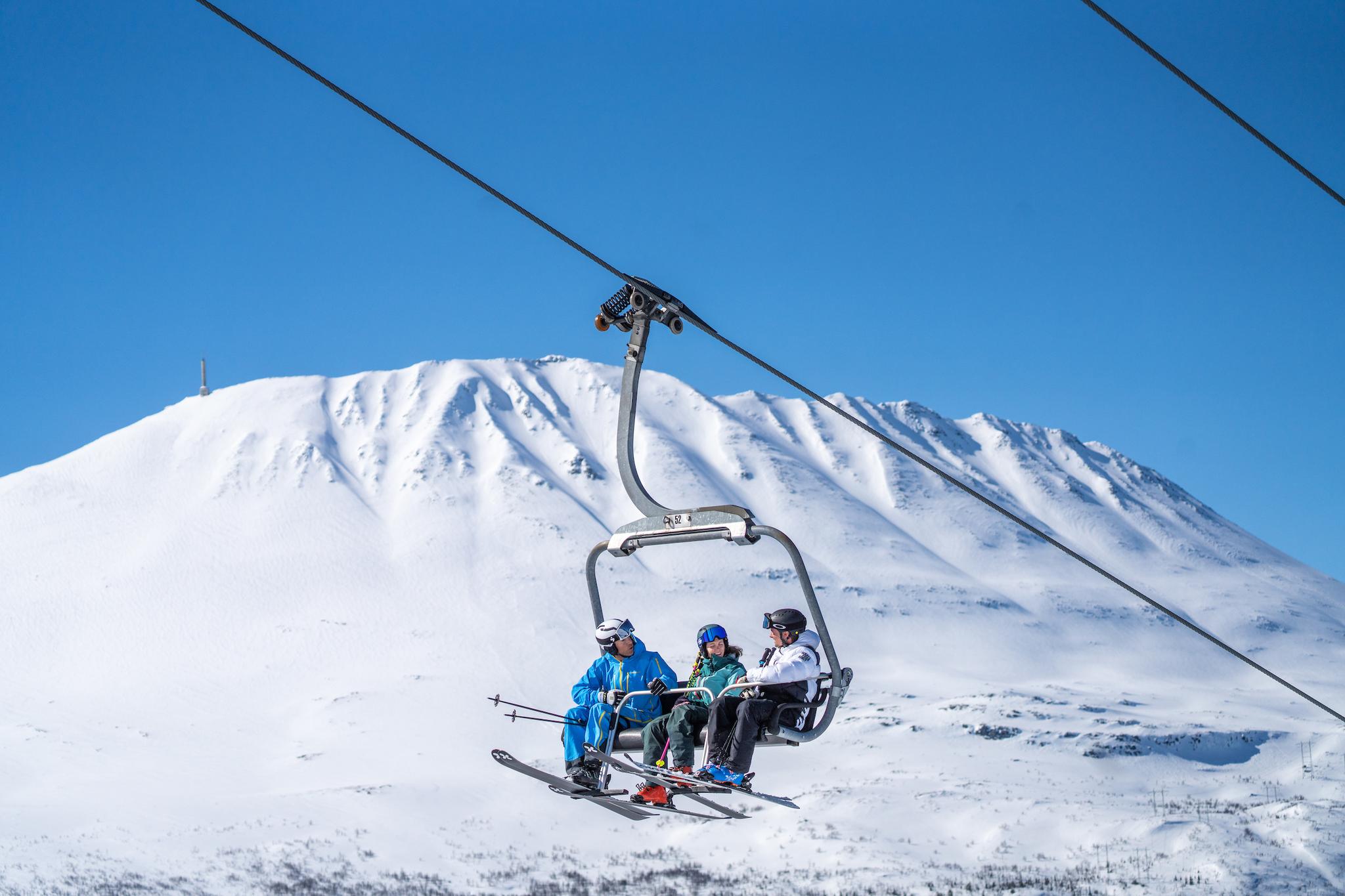 Three people sitting at a ski lift at Gausta ski resort in Telemark