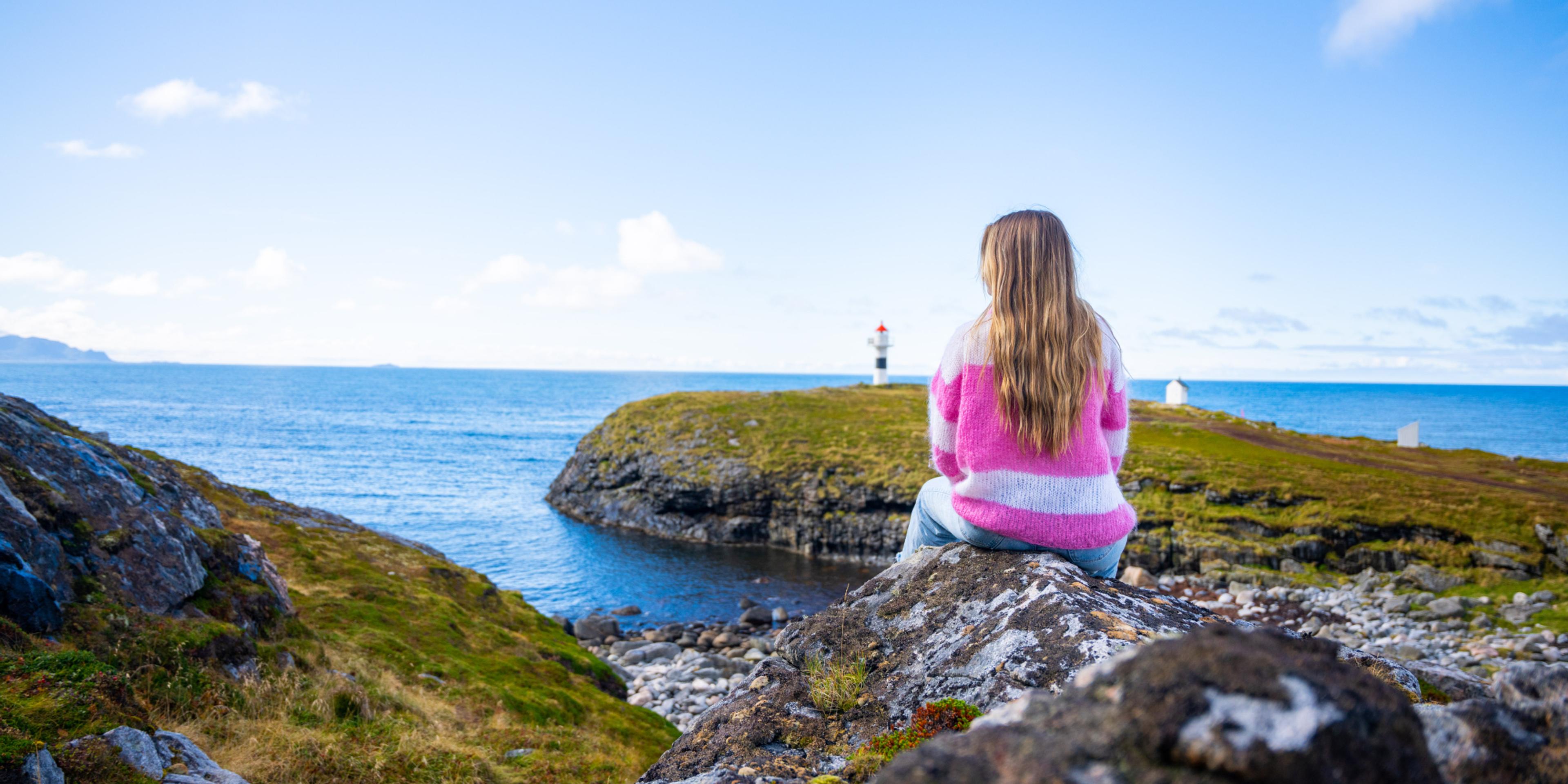 A woman looking at the view of Børhella lighthouse at Andøya, Northern Norway