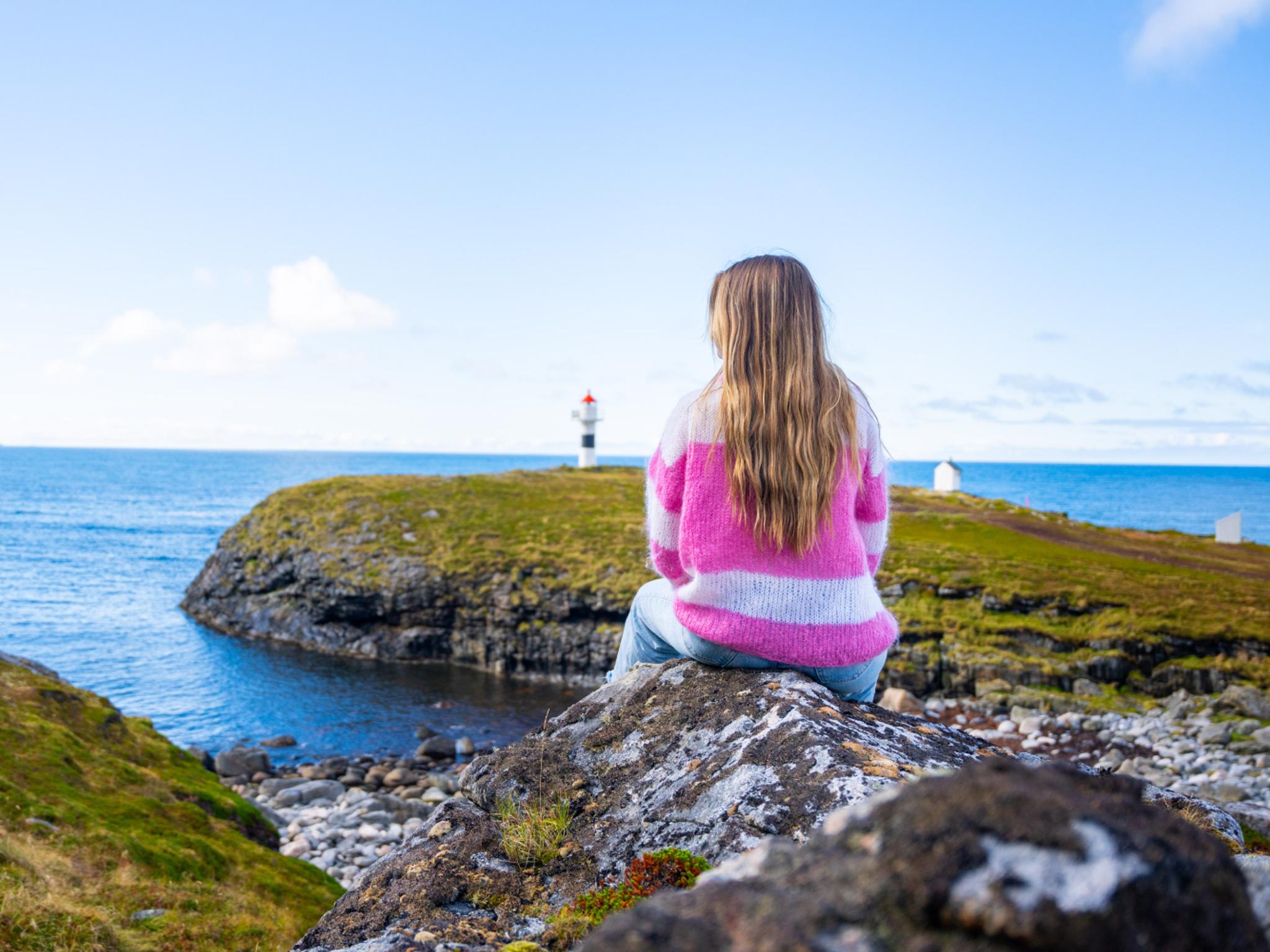 A woman looking at the view of Børhella lighthouse at Andøya, Northern Norway