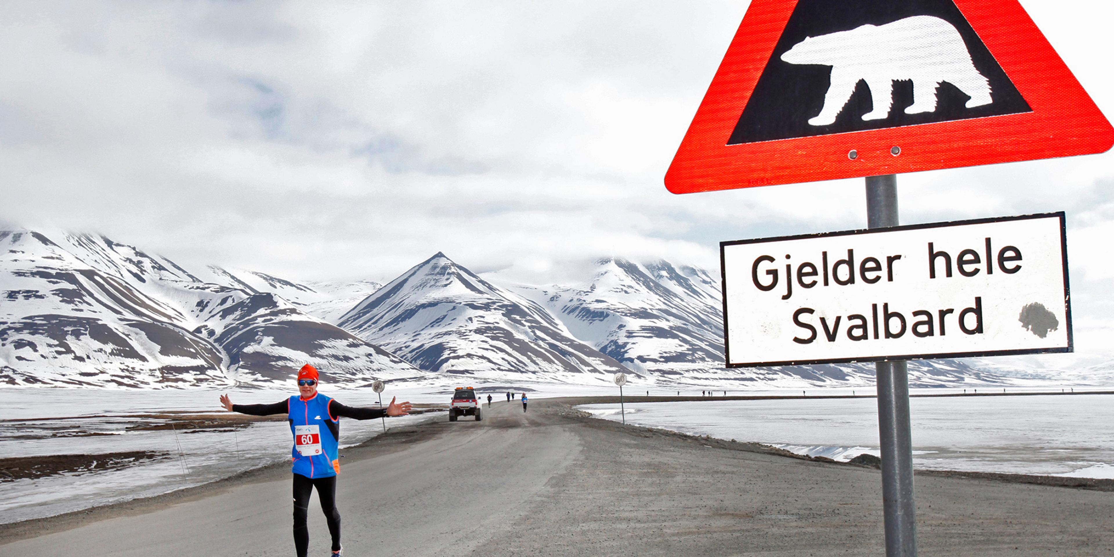 A marathon runner passing a polar bear warning sign in Spitsbergen in Svalbard