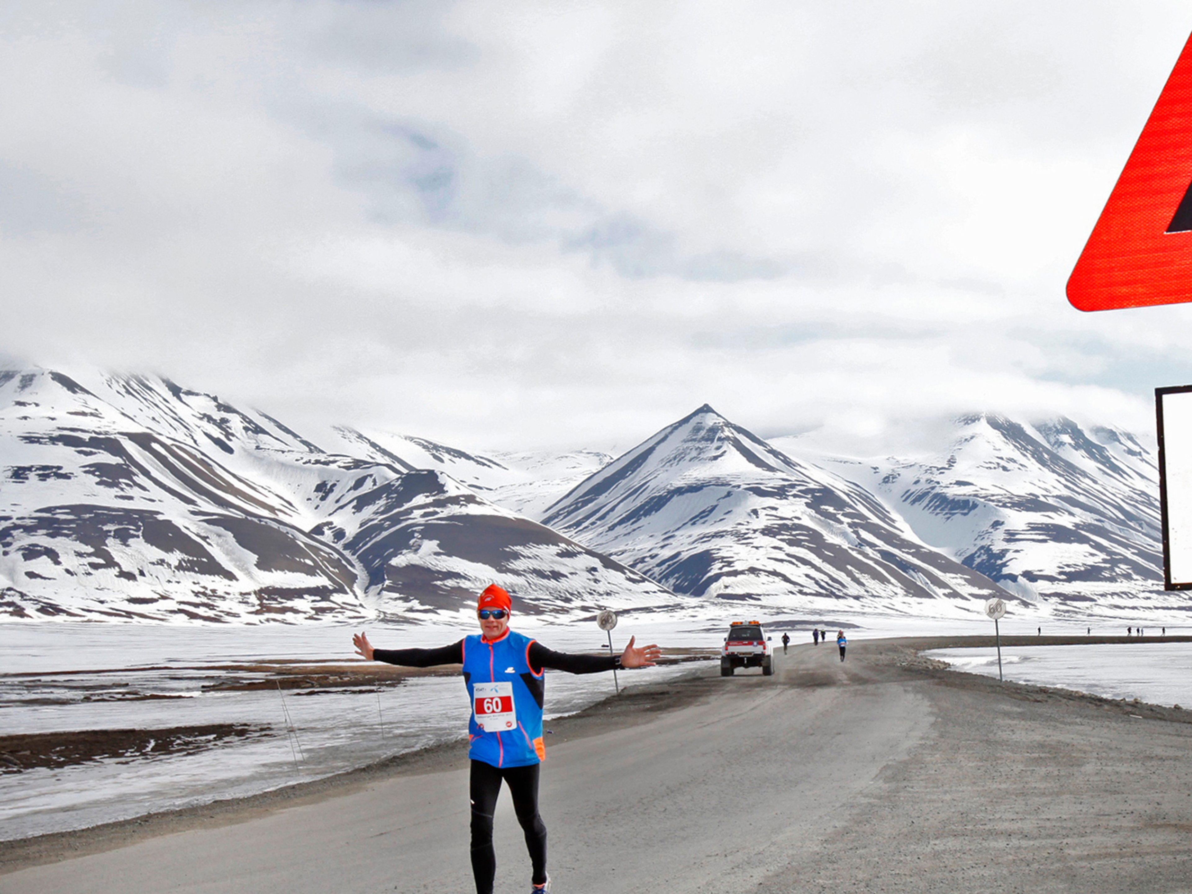 A marathon runner passing a polar bear warning sign in Spitsbergen in Svalbard