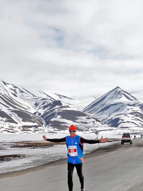 A marathon runner passing a polar bear warning sign in Spitsbergen in Svalbard