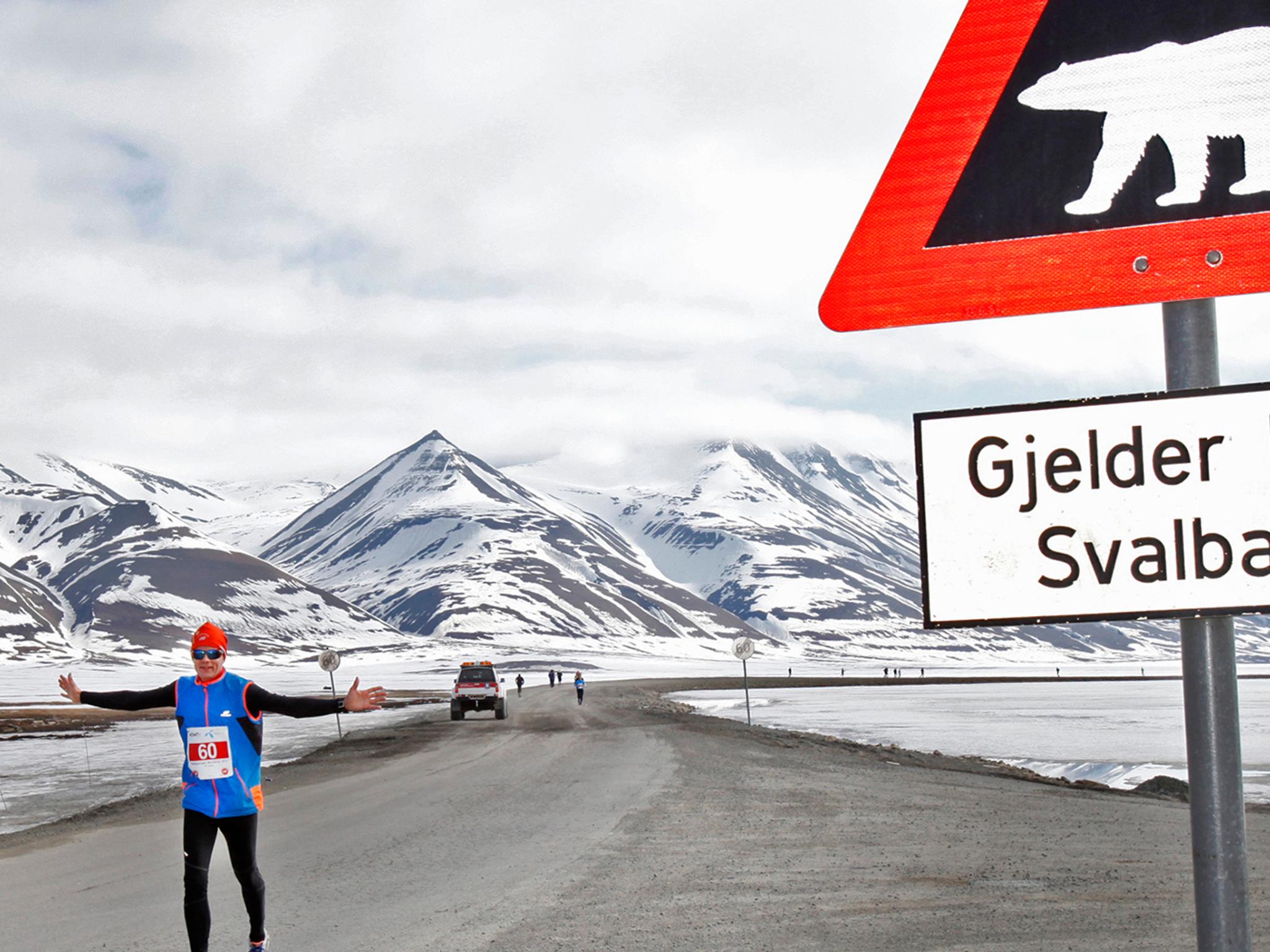 En maratonløper passerer et isbjørnskilt på Spitsbergen, Svalbard
