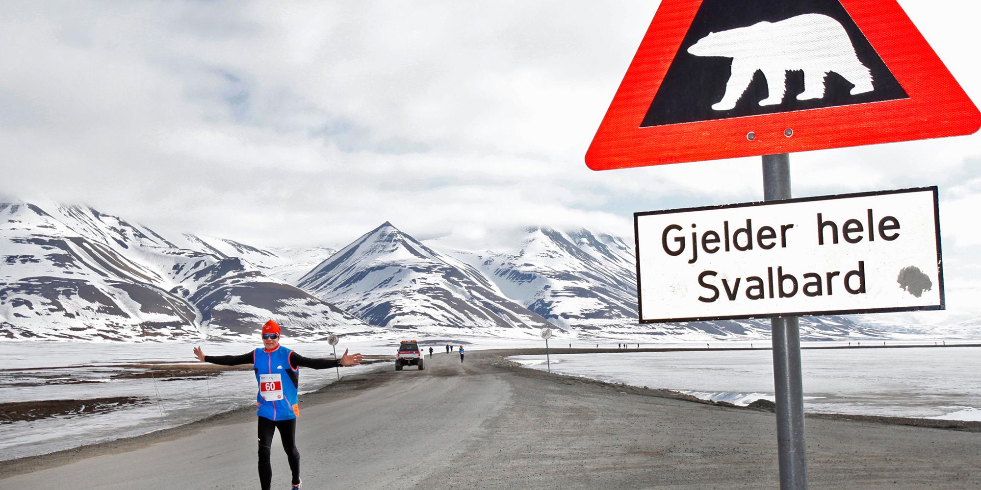 A marathon runner passing a polar bear warning sign in Spitsbergen in Svalbard