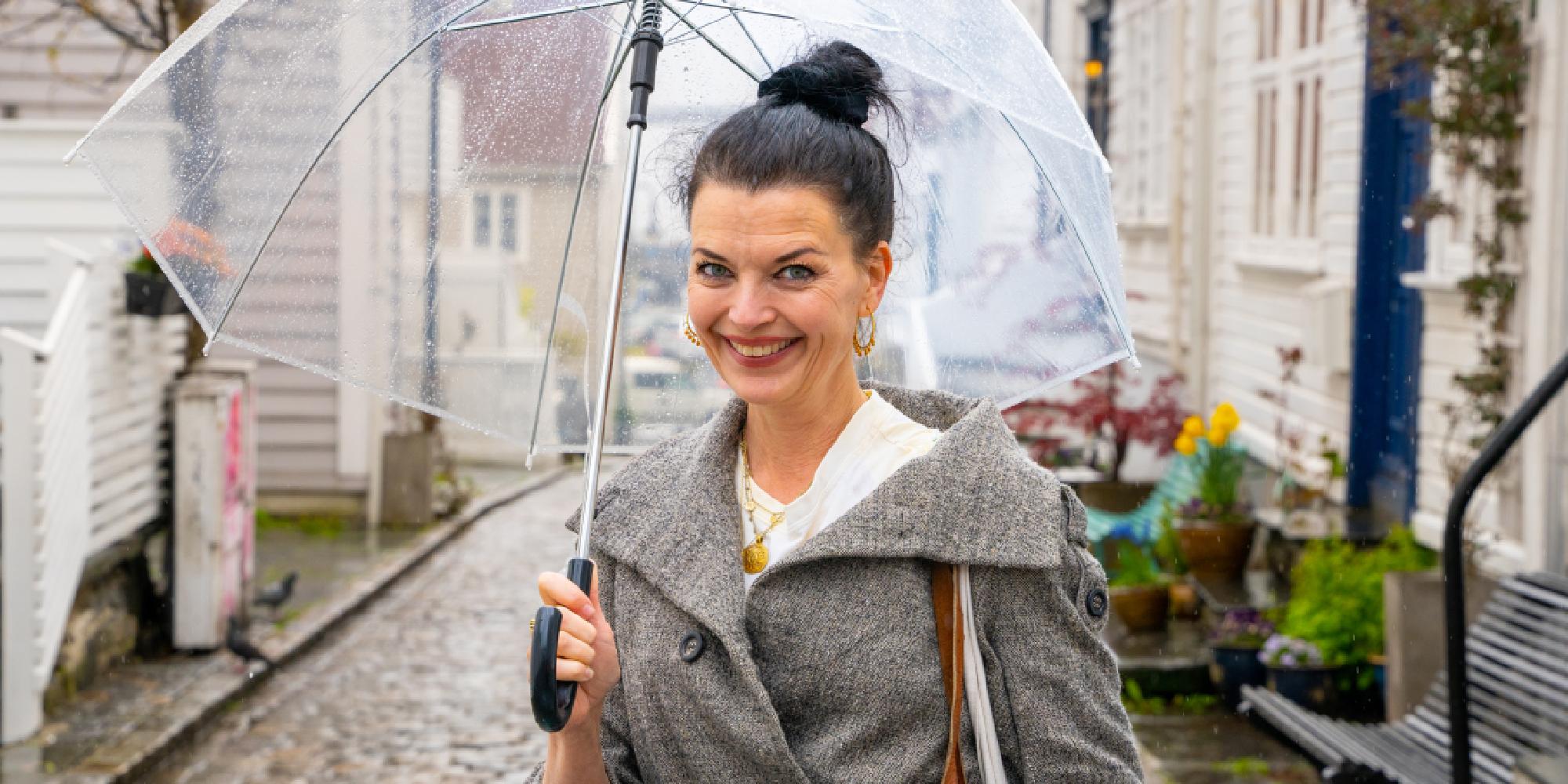 A woman stands under an umbrella in the Pedersgata street in Stavanger, Fjord Norway.