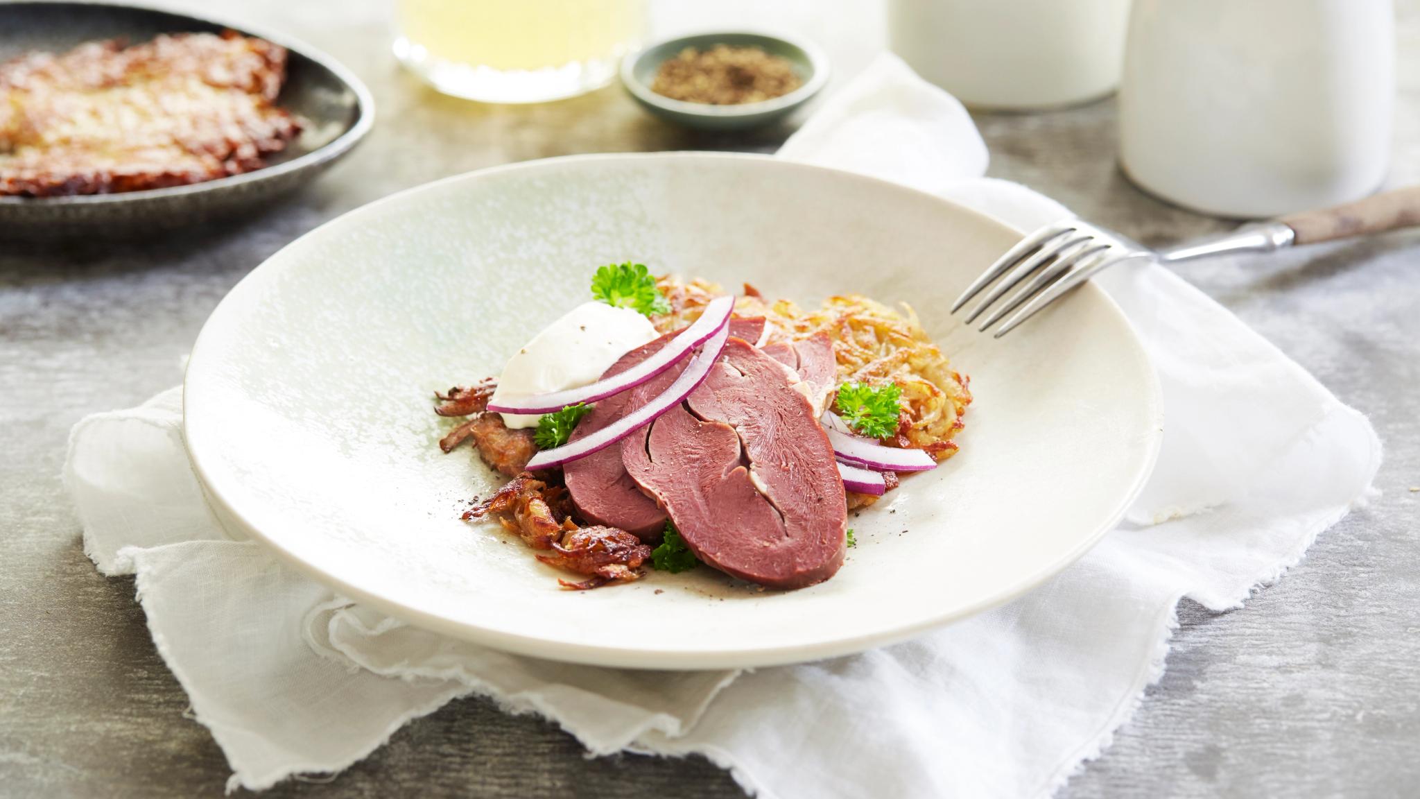 A bowl of smoked reindeer heart served with potatoes and salad in Norway