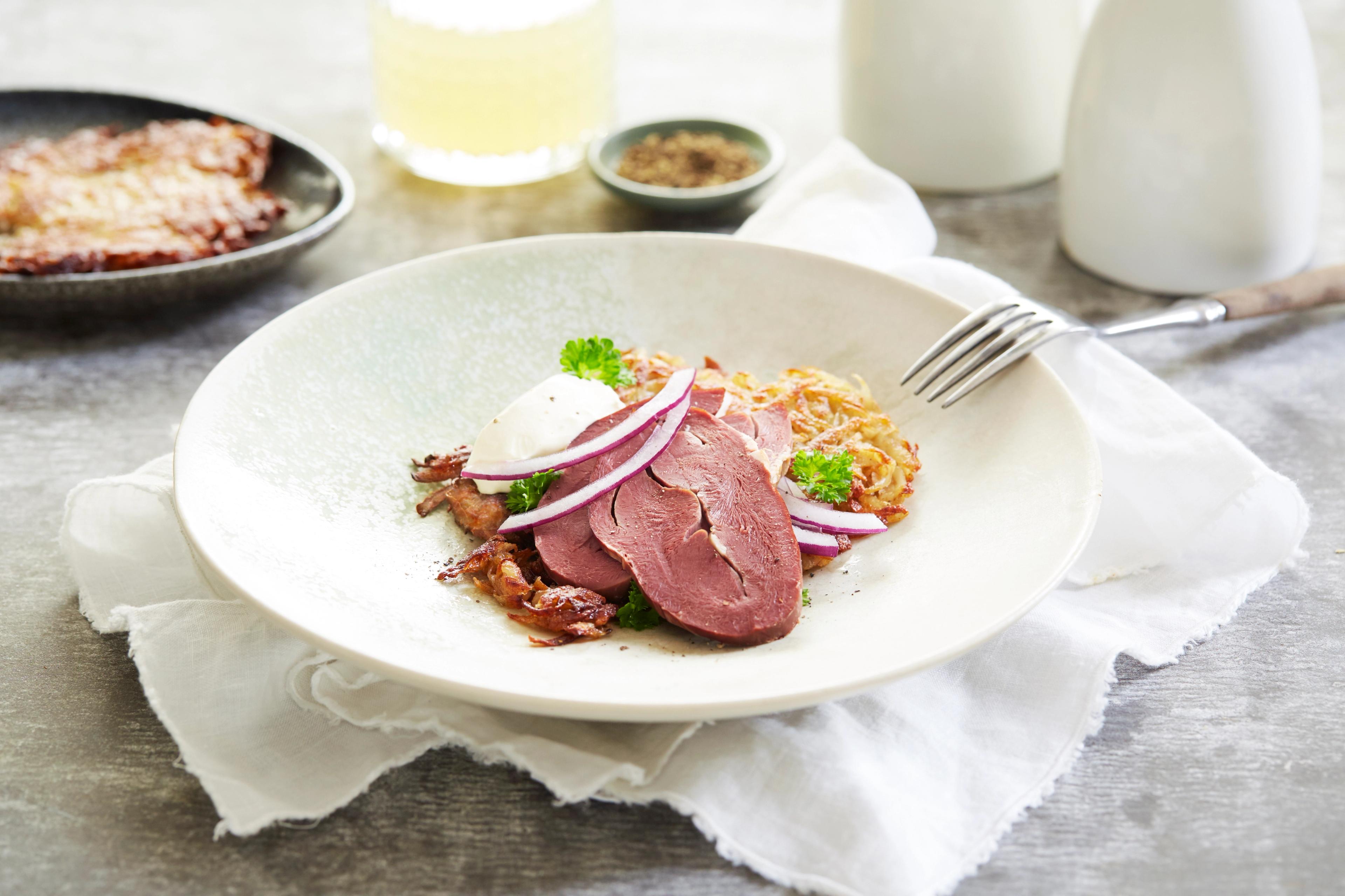 A bowl of smoked reindeer heart served with potatoes and salad in Norway