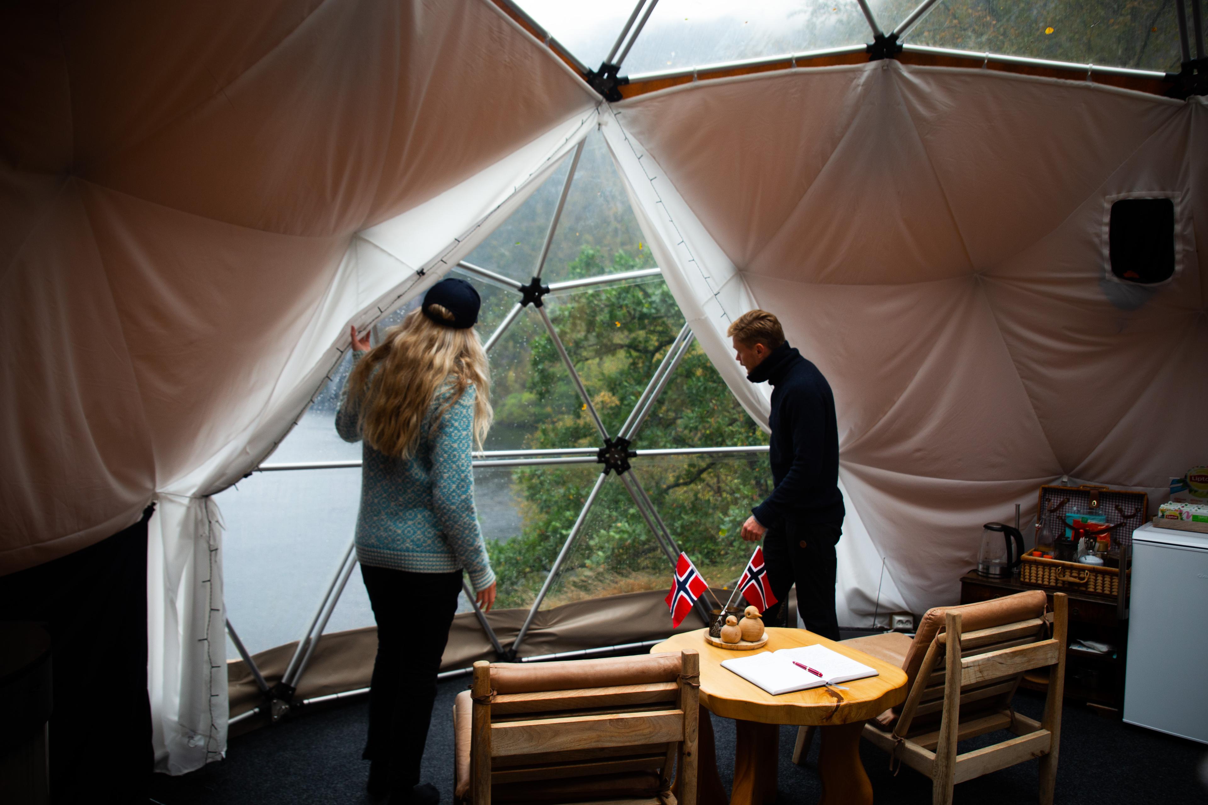 Two people in a dome, looking out at nature.