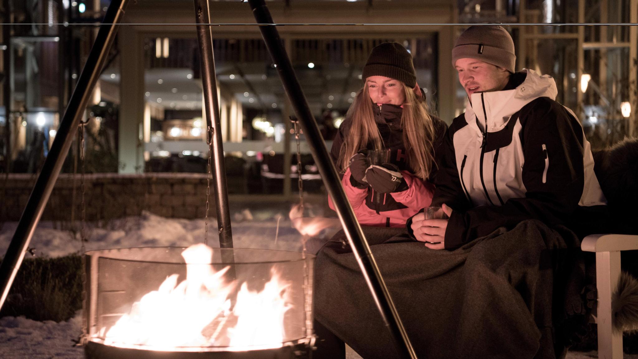 People sitting around the bonfire outside Fretheim Hotel in Flåm