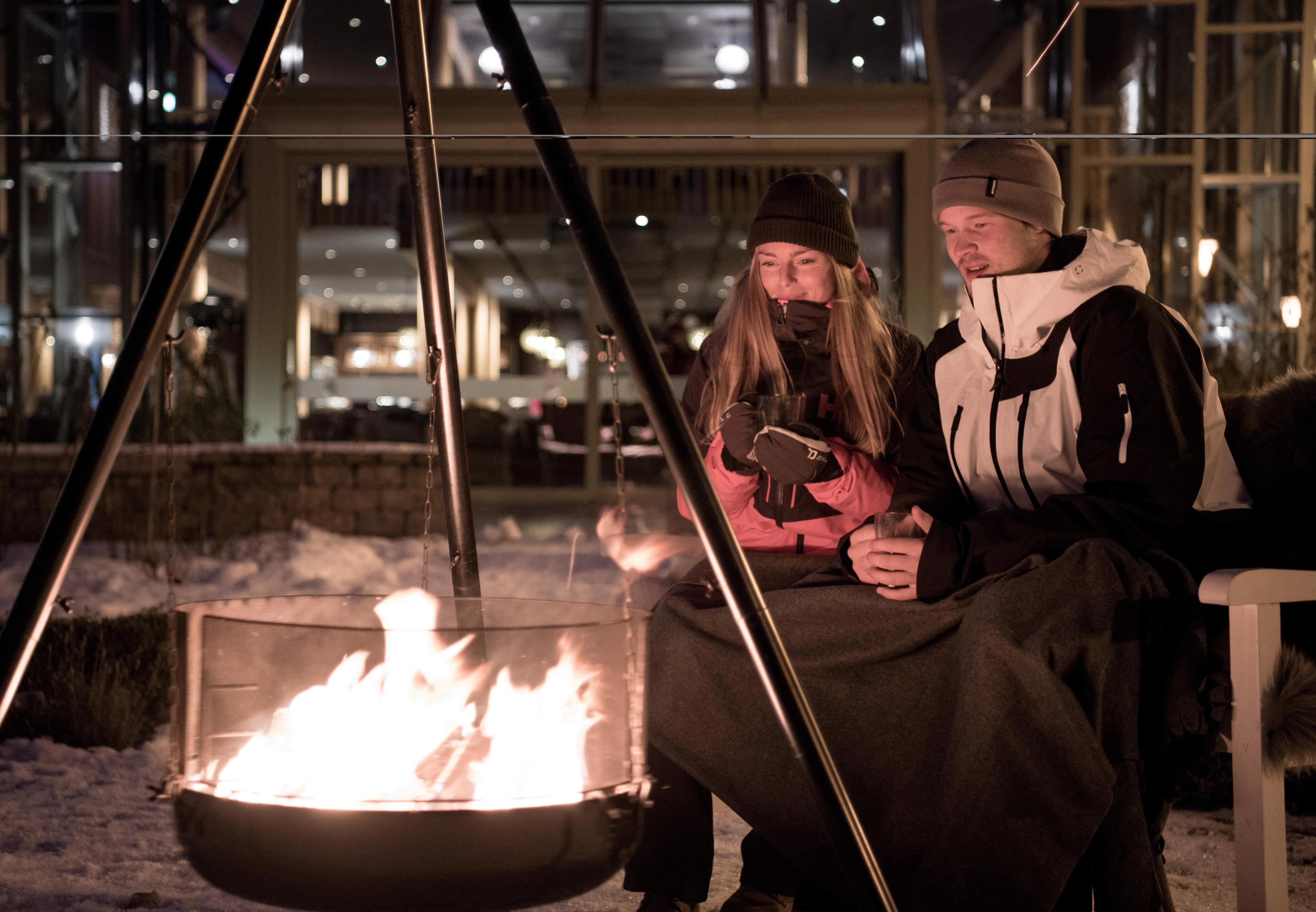 People sitting around the bonfire outside Fretheim Hotel in Flåm