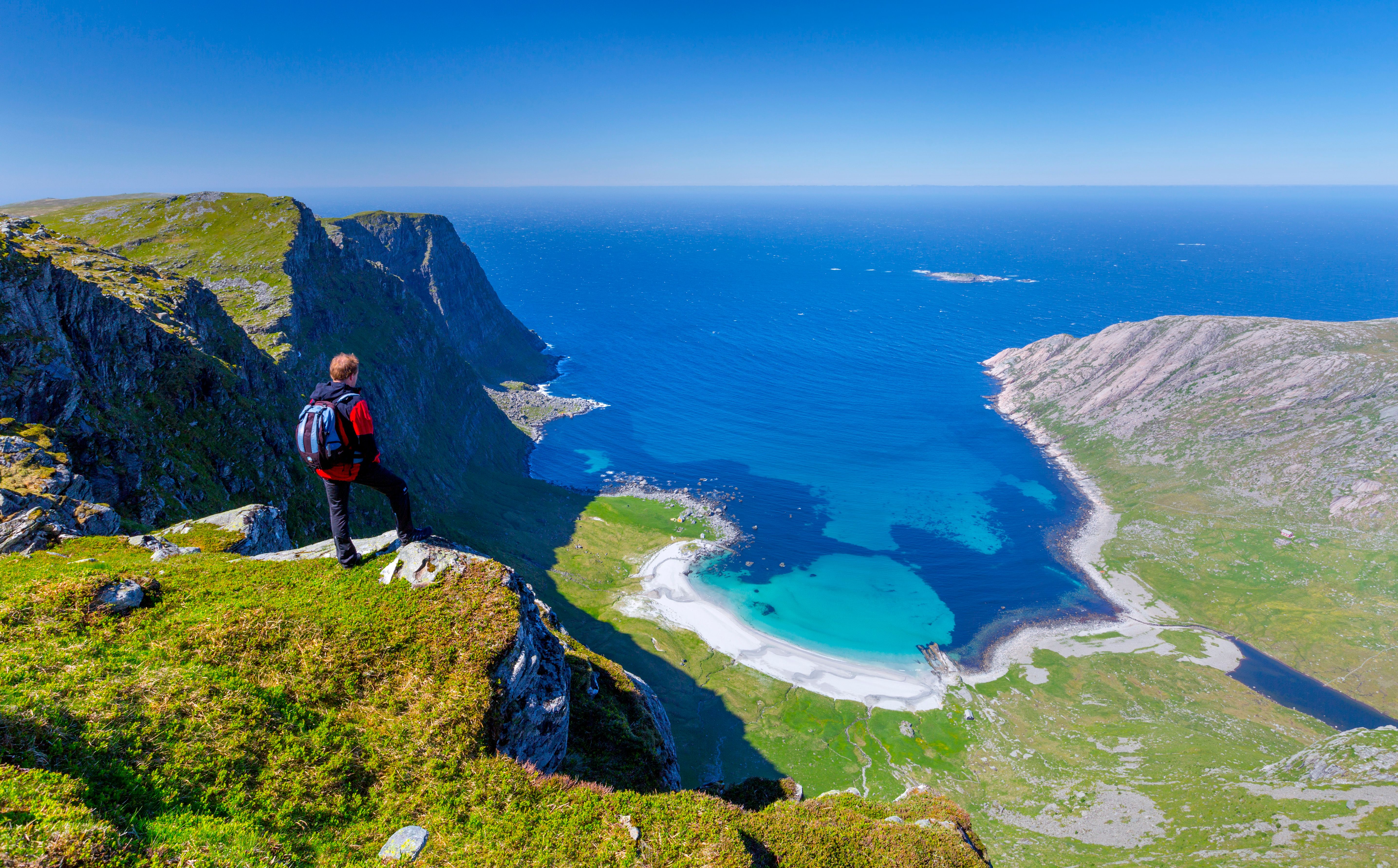 Man standing on the mountain above the beautiful Vetvika beach in Fjord Norway
