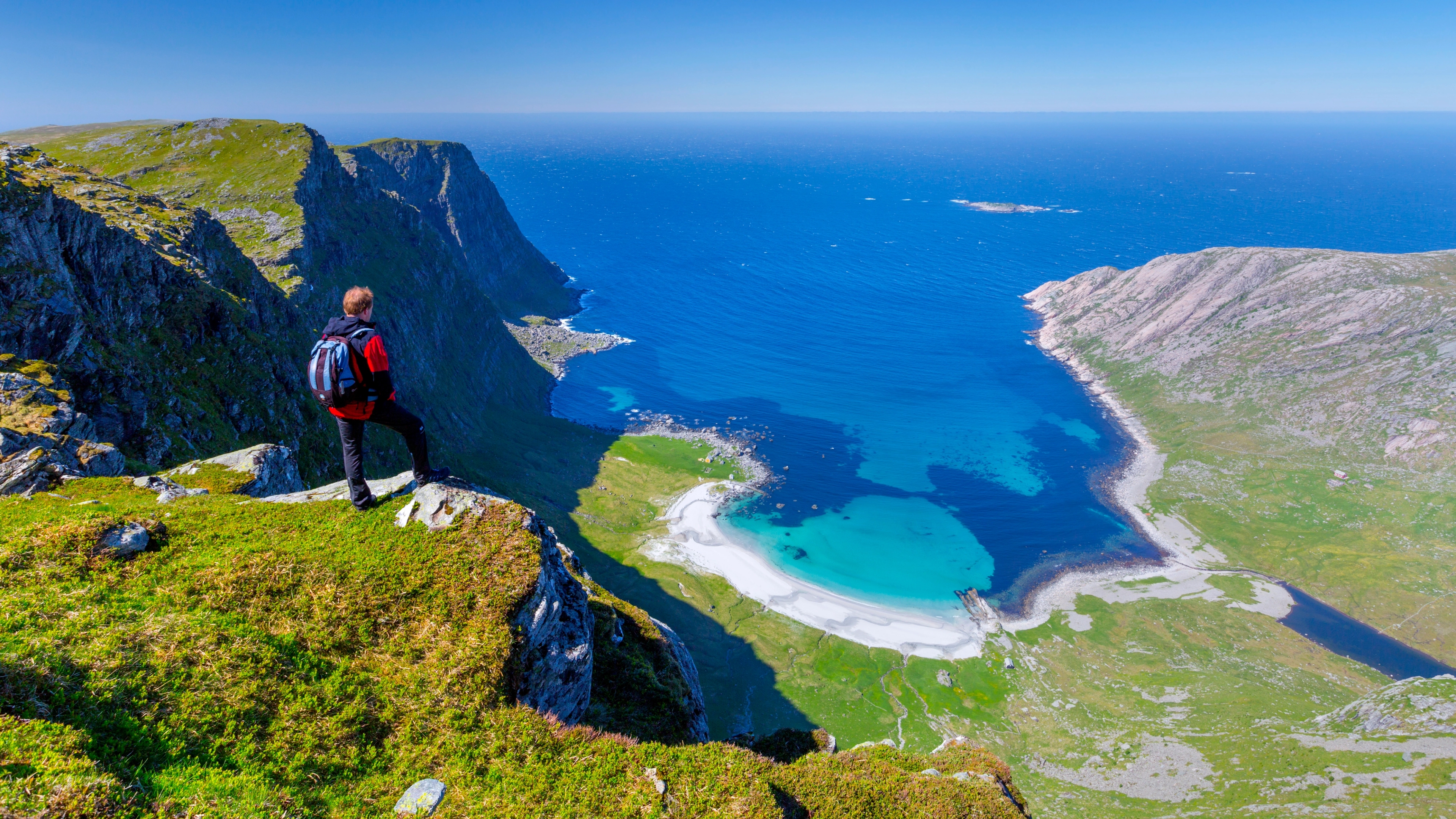 Man standing on the mountain above the beautiful Vetvika beach in Fjord Norway
