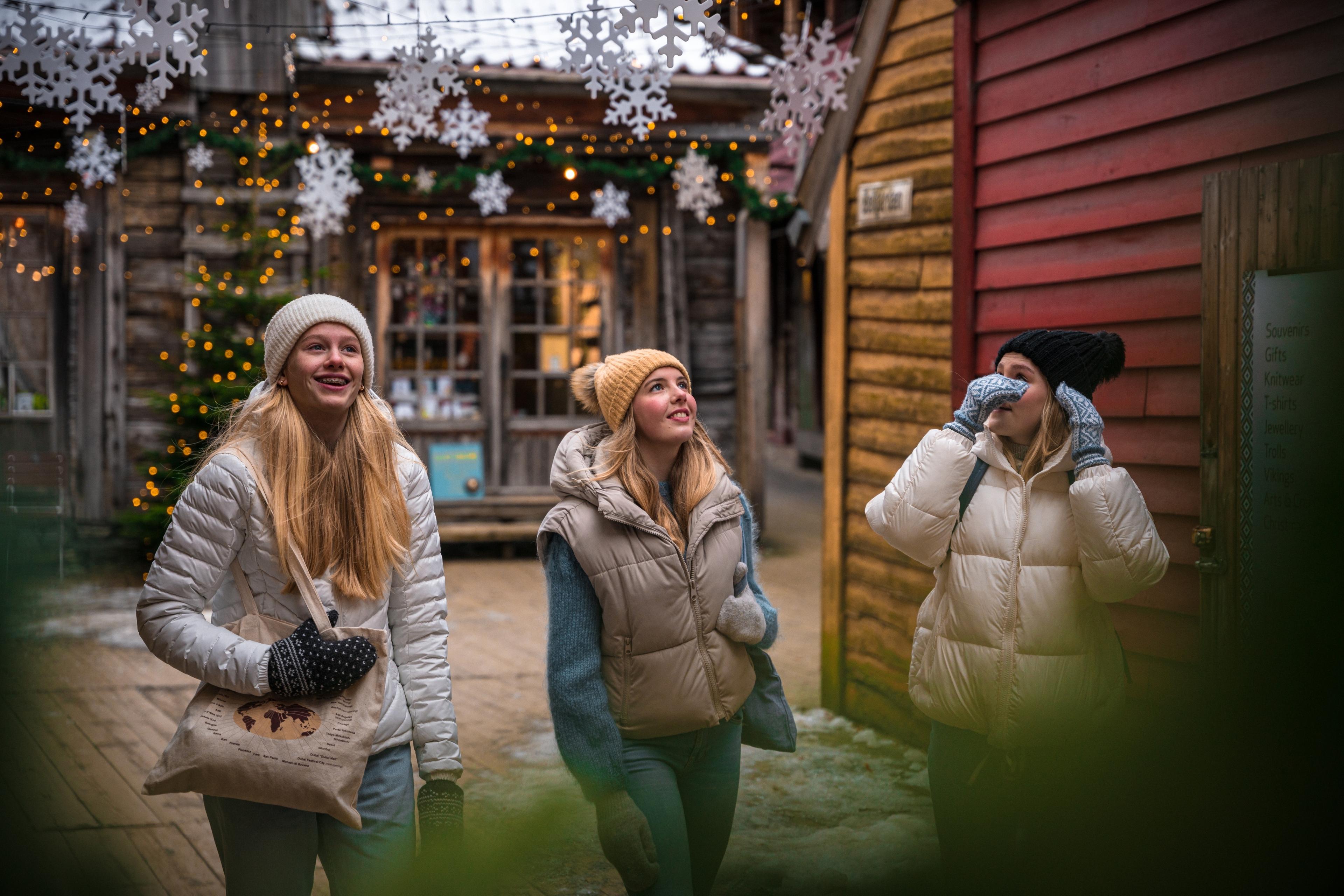 Three girls walking between the Christmassy wooden houses in Bergen, Fjord Norway