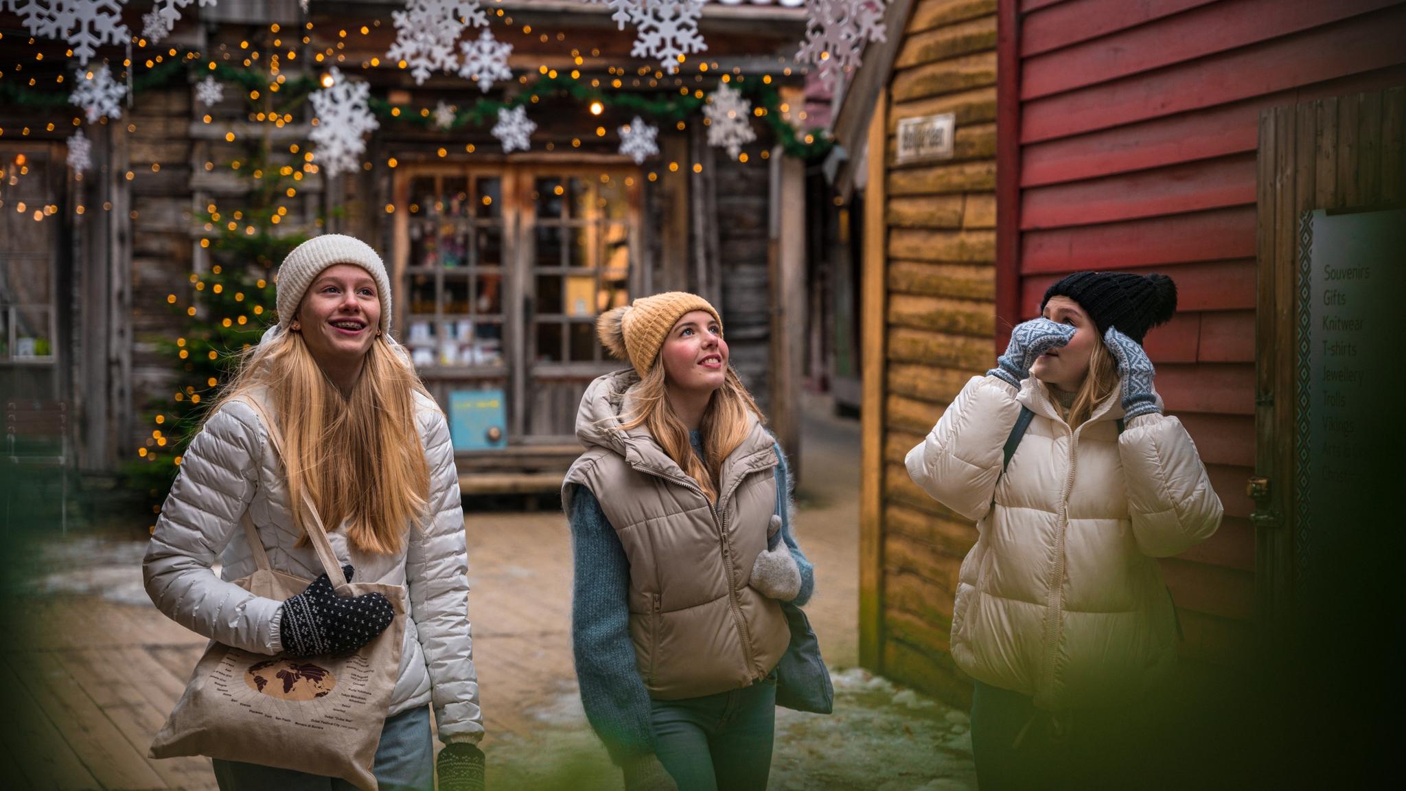 Three girls walking between the Christmassy wooden houses in Bergen, Fjord Norway