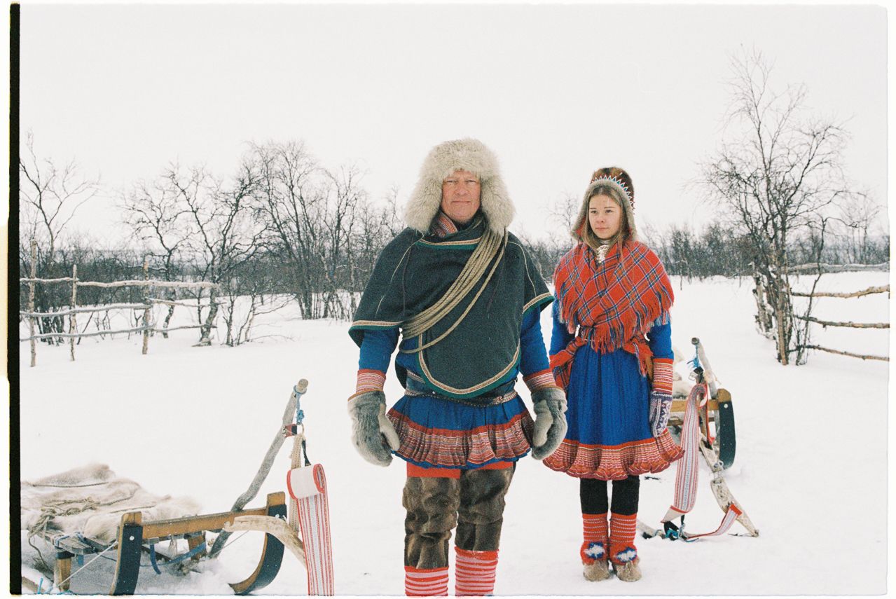 Two Sami people in a snow covered landscape.