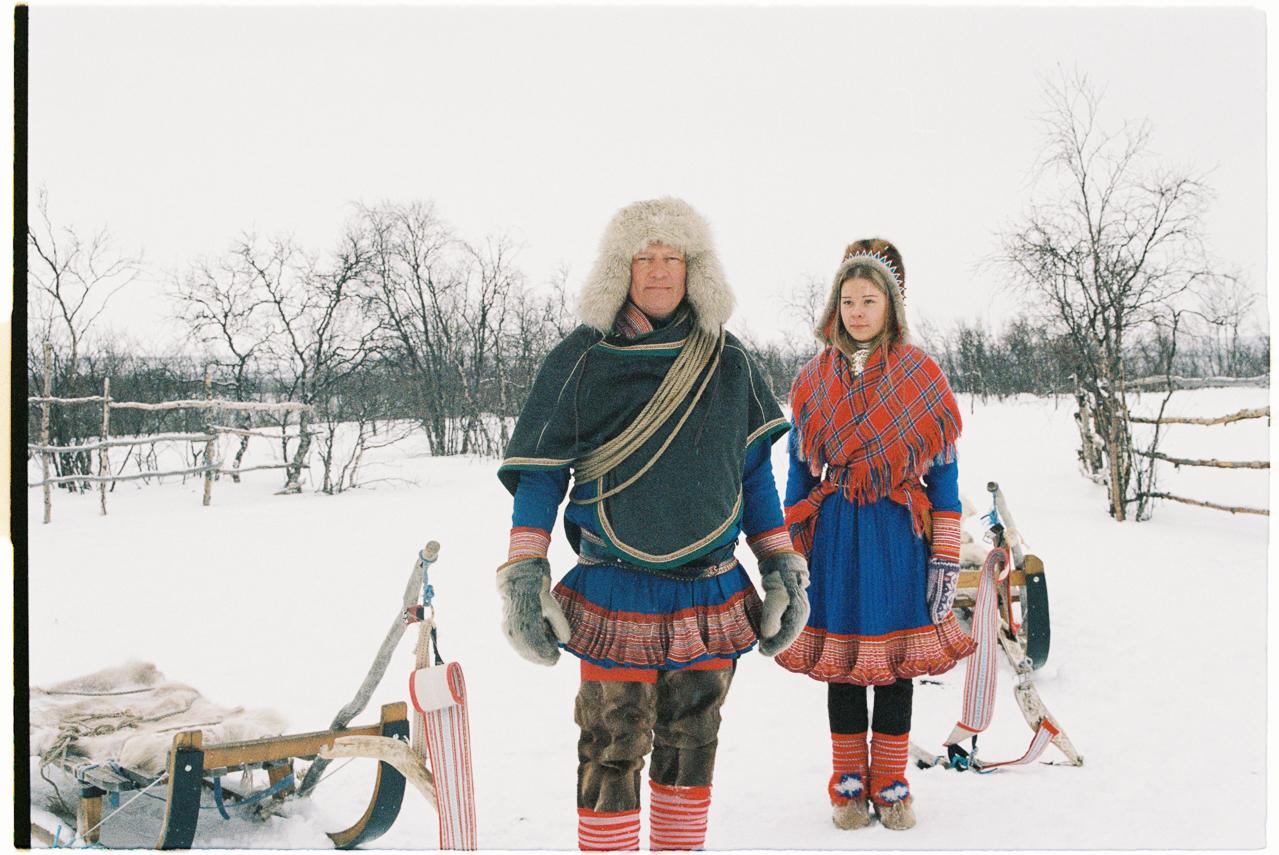 Two Sami people in a snow covered landscape.