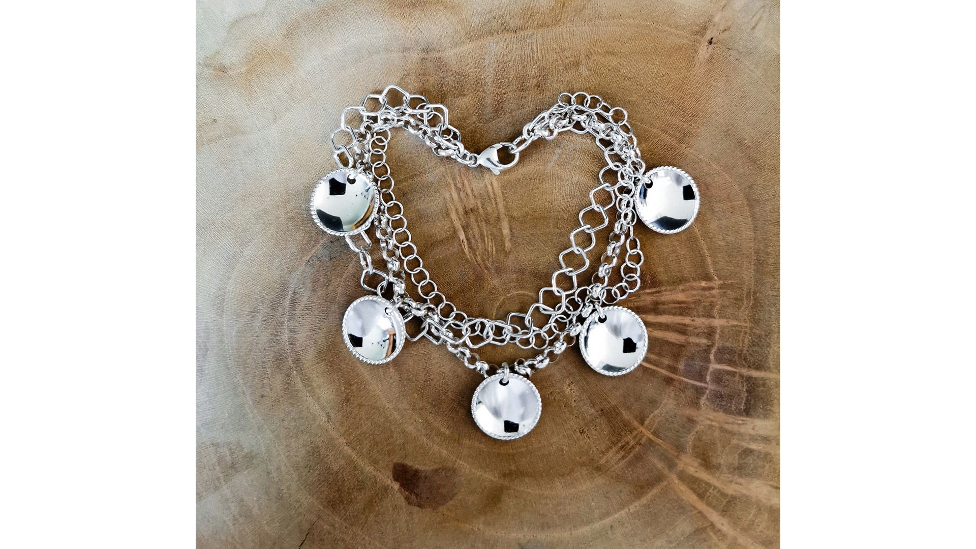 Silver bracelet resting on a slab of wood