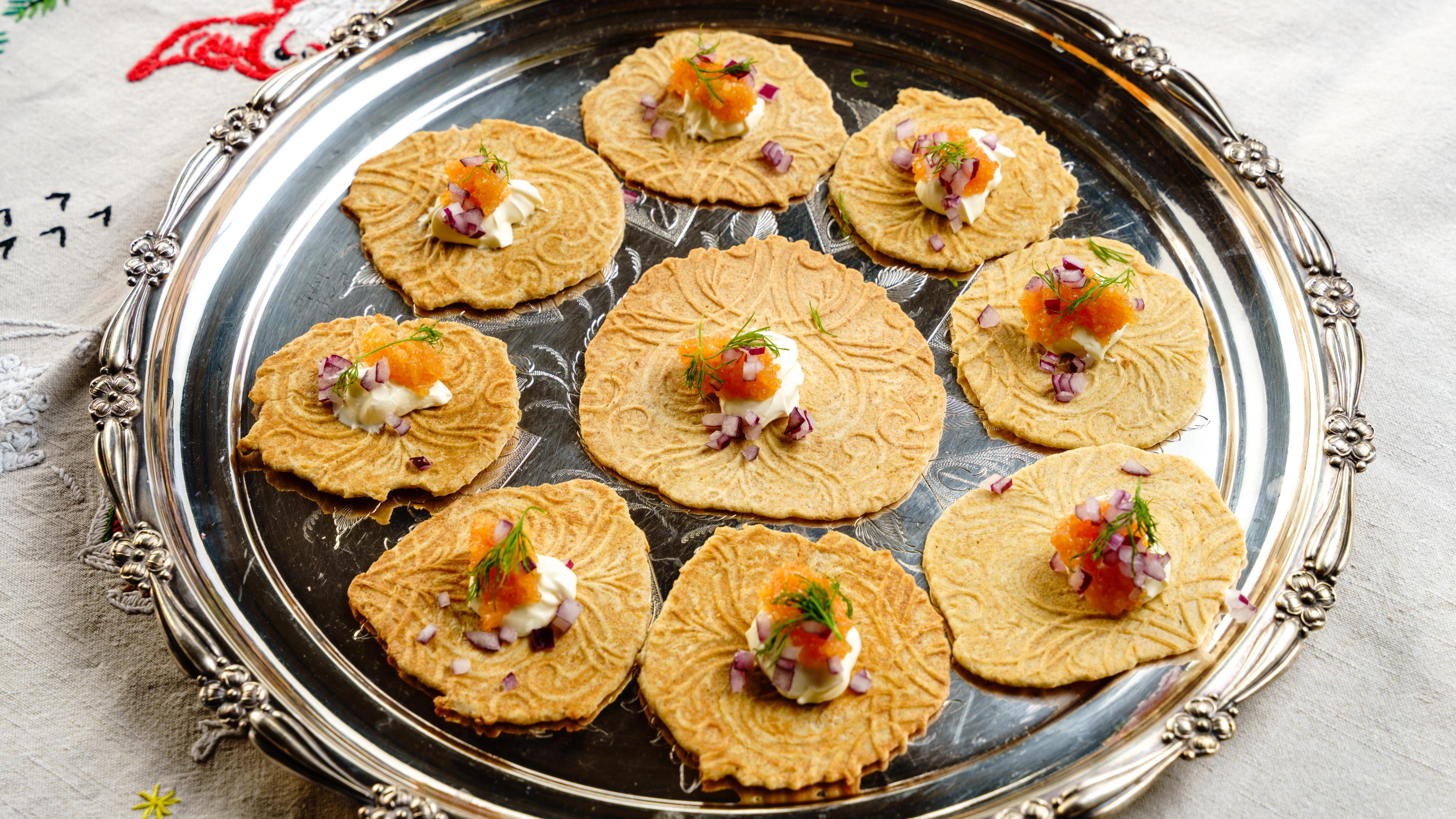 Krumkaker on a silver plate with salmon roe and sour cream.